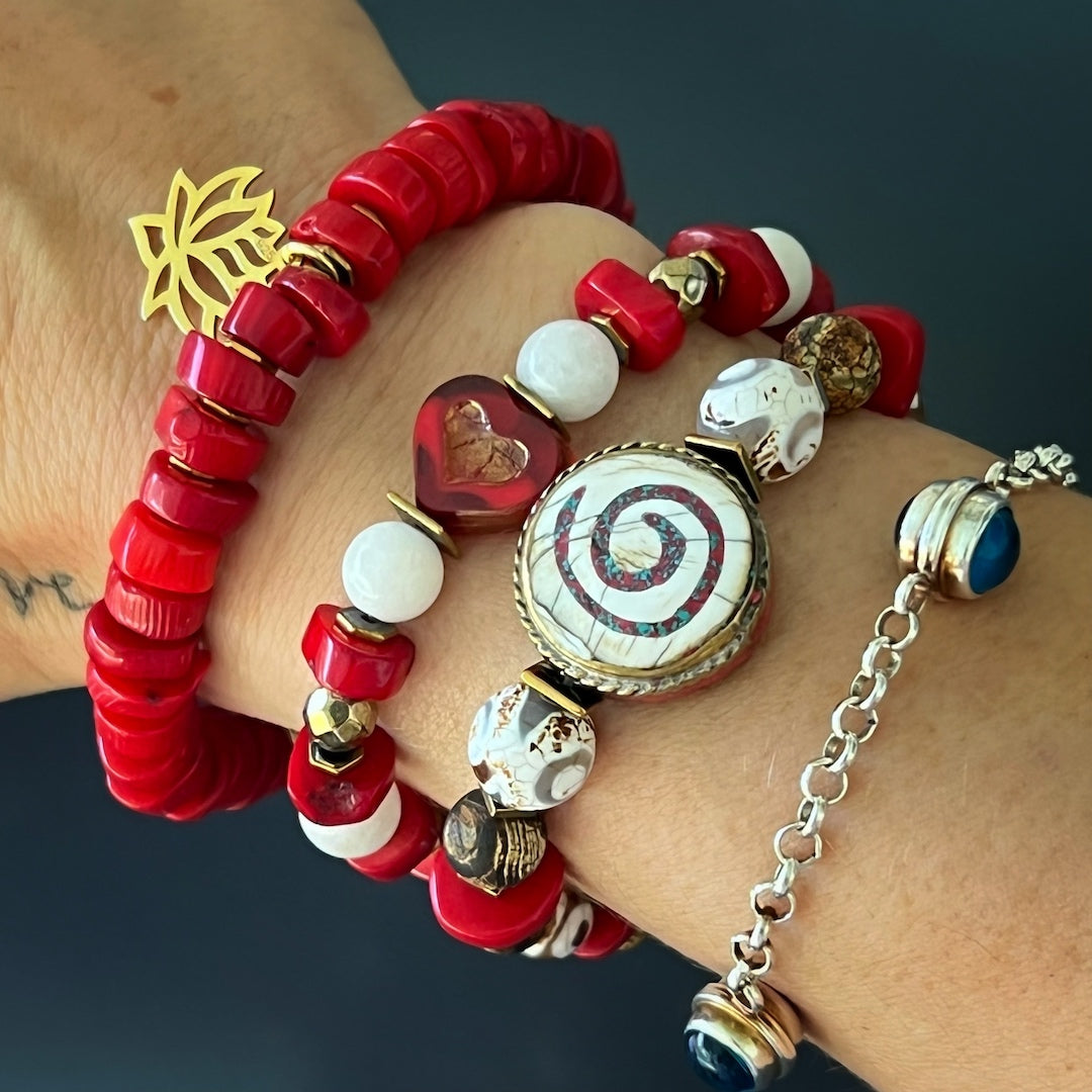 The Yoga Spirit Mystic Bracelet beautifully complements the hand model's style, showcasing the coral stone beads, Nepal meditation beads, and the spiritual essence of the spiral charm.