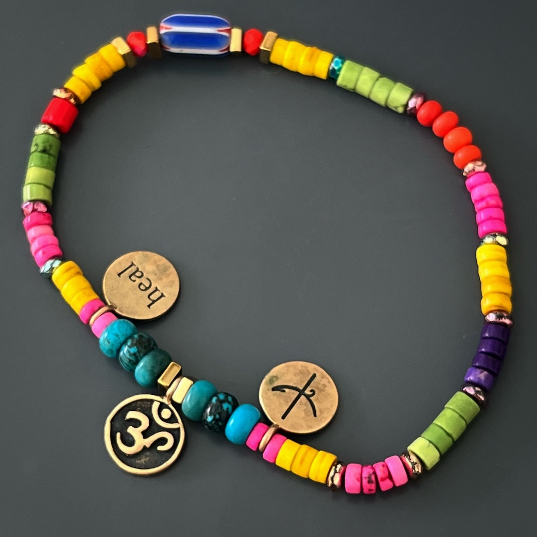 The Yogi Dream Anklet embodies the essence of intention and self-care, with bronze gold-plated Om-Dream and Heal charms, turquoise stone beads, and colorful howlite stone beads, inspiring peace, balance, and healing.