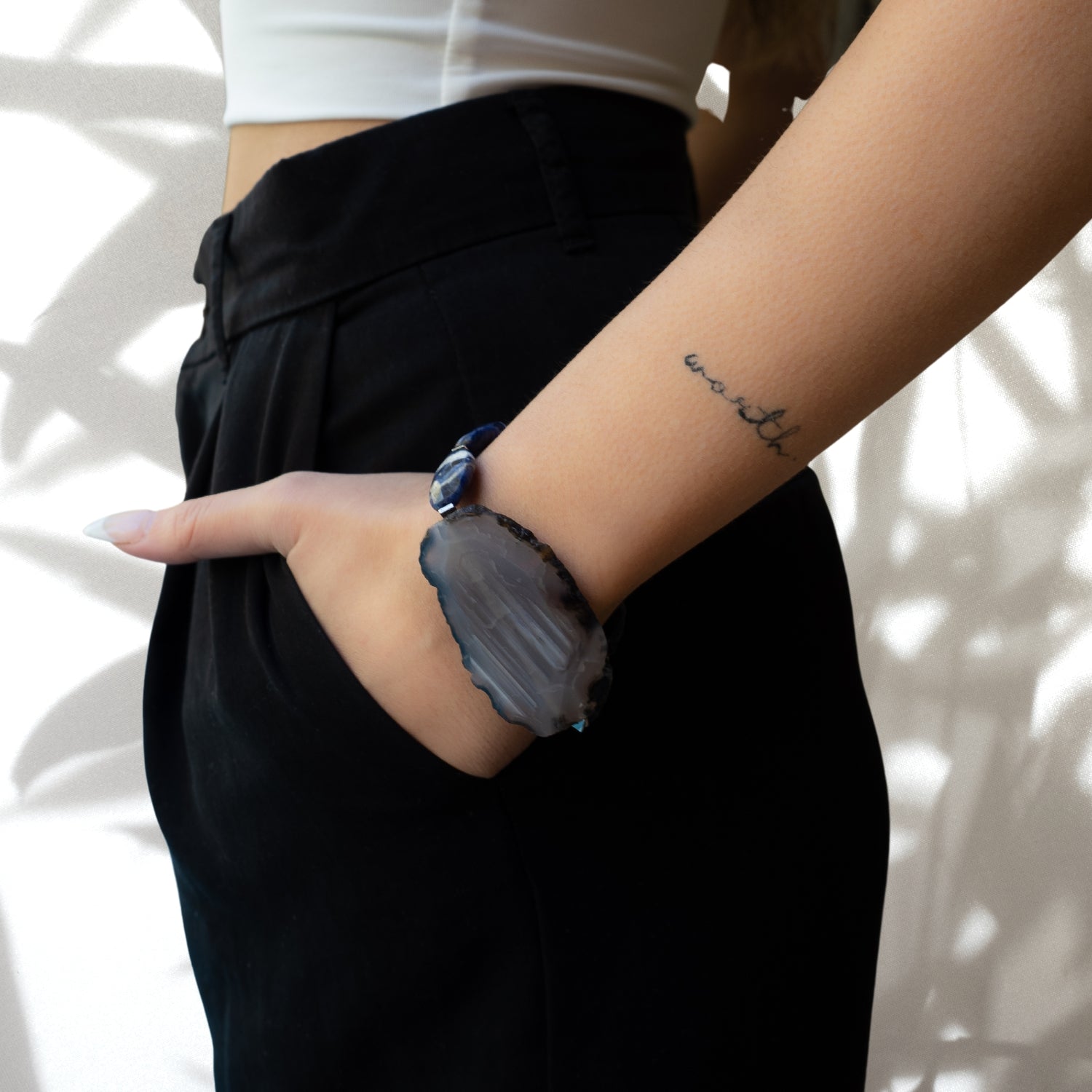 Model wearing Agate Spiritual Balance Bracelet; a stunning and meaningful accessory featuring natural raw agate stone, flat blue and white sodalite stone beads, and Swarovski crystals.