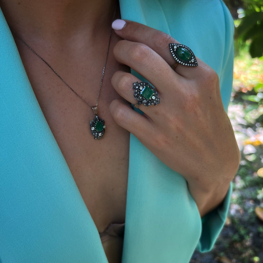 Close-up of a hand model wearing the Emerald & Diamond Eye Ring, highlighting the exquisite craftsmanship and the vivid green color of the emerald.