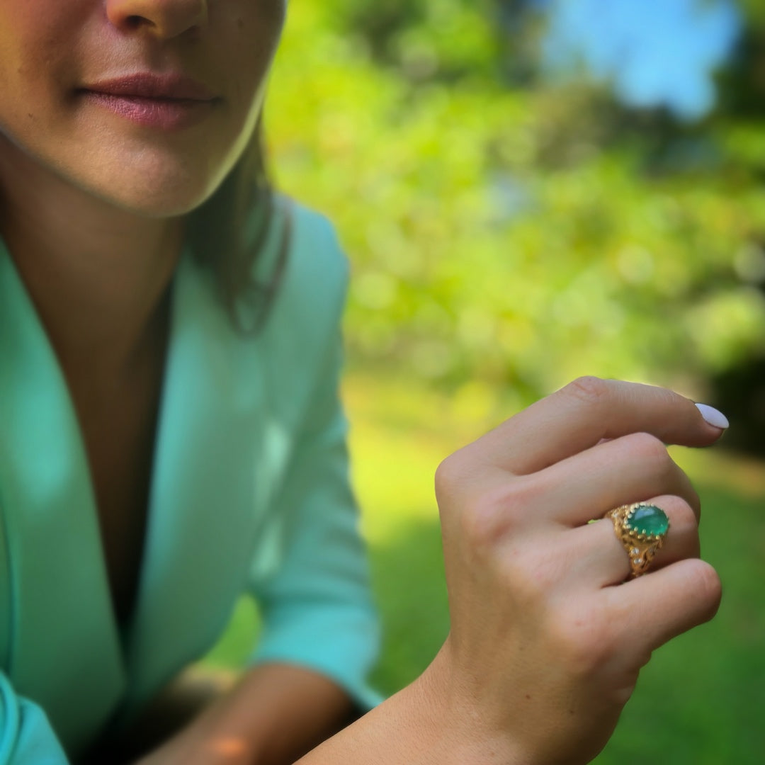 Close-up of a hand model wearing the Emerald & Diamond Teardrop Ring, showcasing the intricate details of the teardrop design and the vibrant green of the emerald, complemented by the sparkling diamonds.