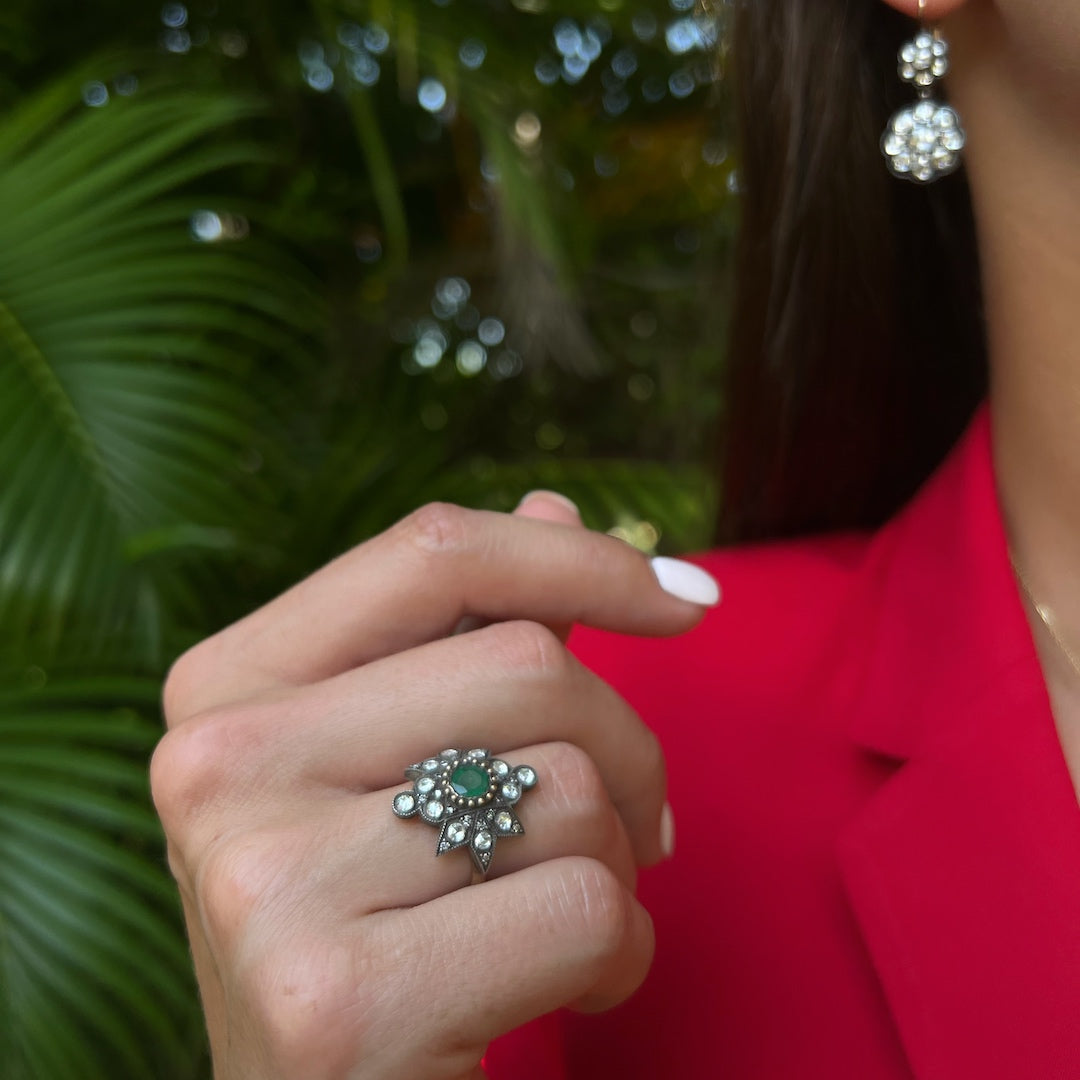 Hand model showcasing the Emerald Star Ring, symbolizing renewal and growth with its stunning emerald centerpiece and the sparkle of diamonds, adding a touch of luxury and sophistication to any ensemble.