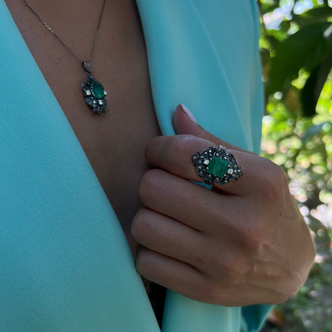 Hand model showcasing the exquisite Emerald Vintage Ring, crafted with precision and attention to detail, featuring a vibrant green emerald surrounded by sparkling diamonds, a true symbol of love and fidelity.