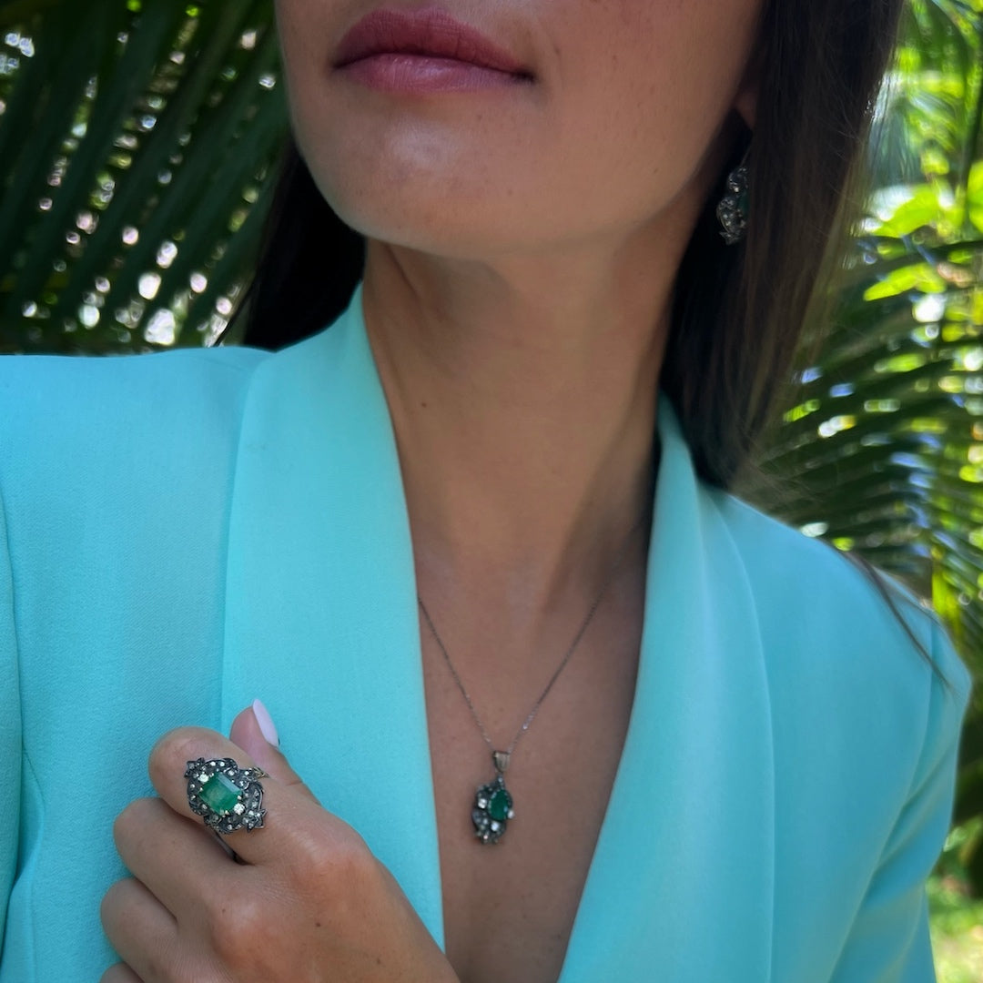 Close-up of a hand model wearing the Emerald Vintage Ring, highlighting the intricate design and the captivating beauty of the emerald gemstone, complemented by the shimmering diamonds, creating a timeless and elegant piece of jewelry.