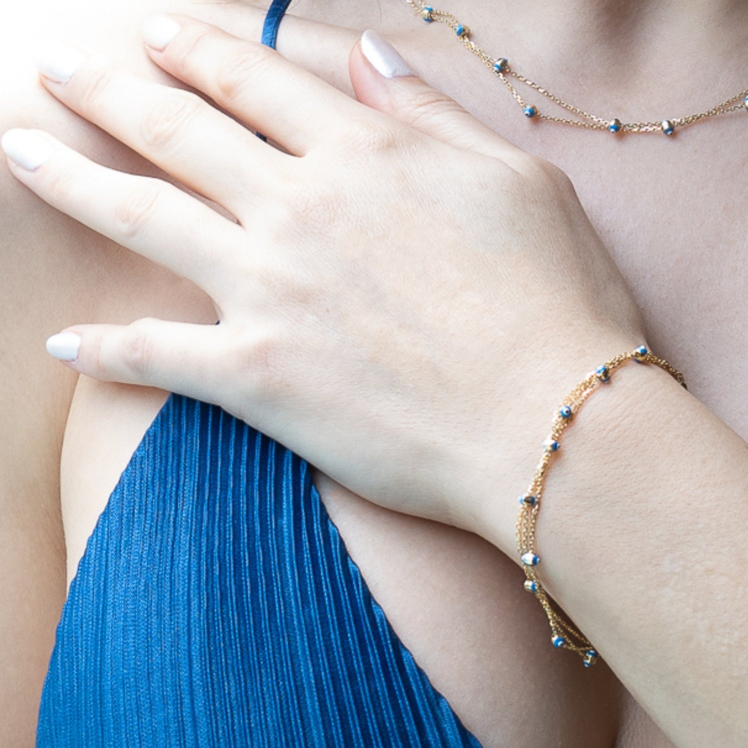 Stylish Bracelet on Hand Model - The Gold Evil Eye Triple Bracelet adorning the wrist of a confident hand model.
