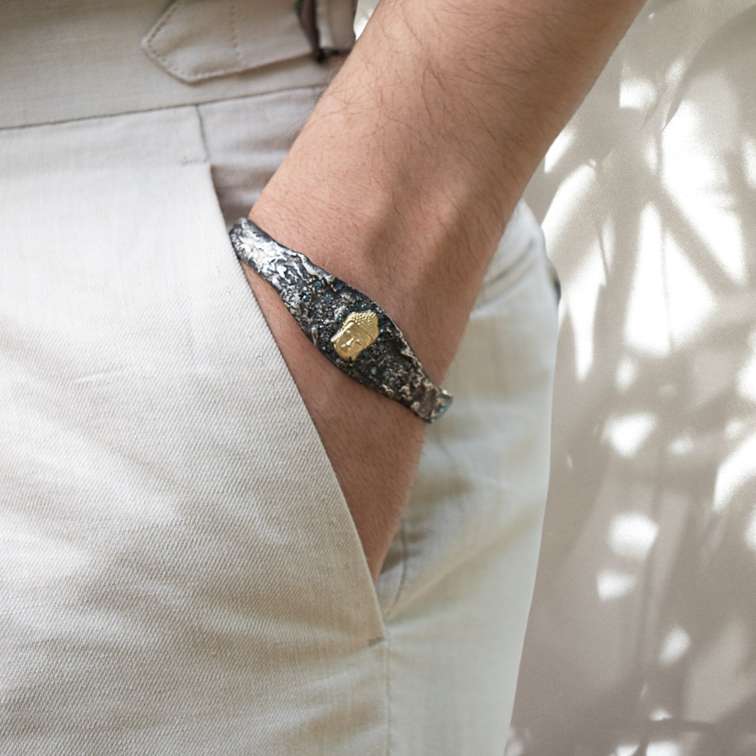 Our hand model proudly showcases the Handmade Buddha Bangle Bracelet, highlighting its intricate design, luxurious materials, and the captivating sparkle of blue diamonds.