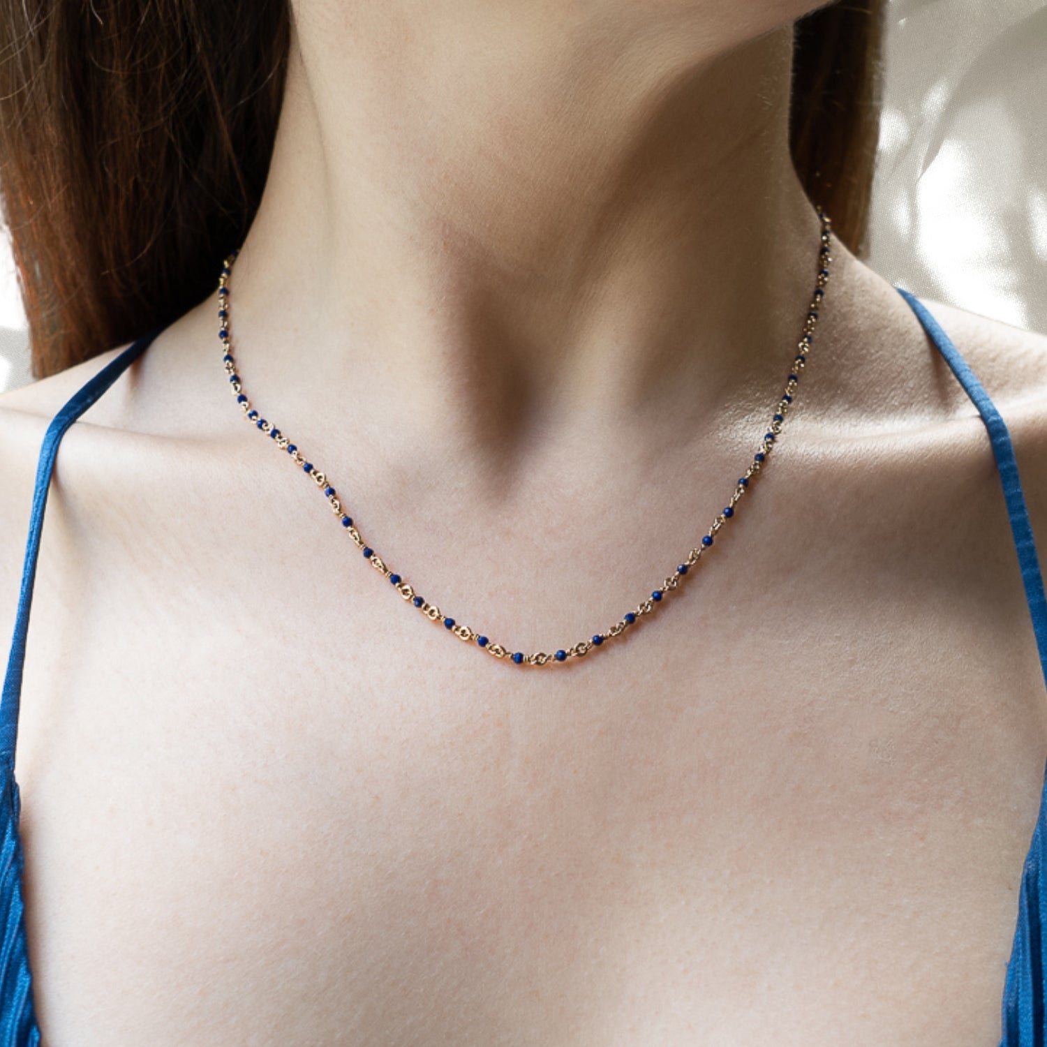 The Karya Lapis Gold Necklace gracefully adorns the neckline of the model, accentuating her natural beauty and adding a touch of elegance to her ensemble.