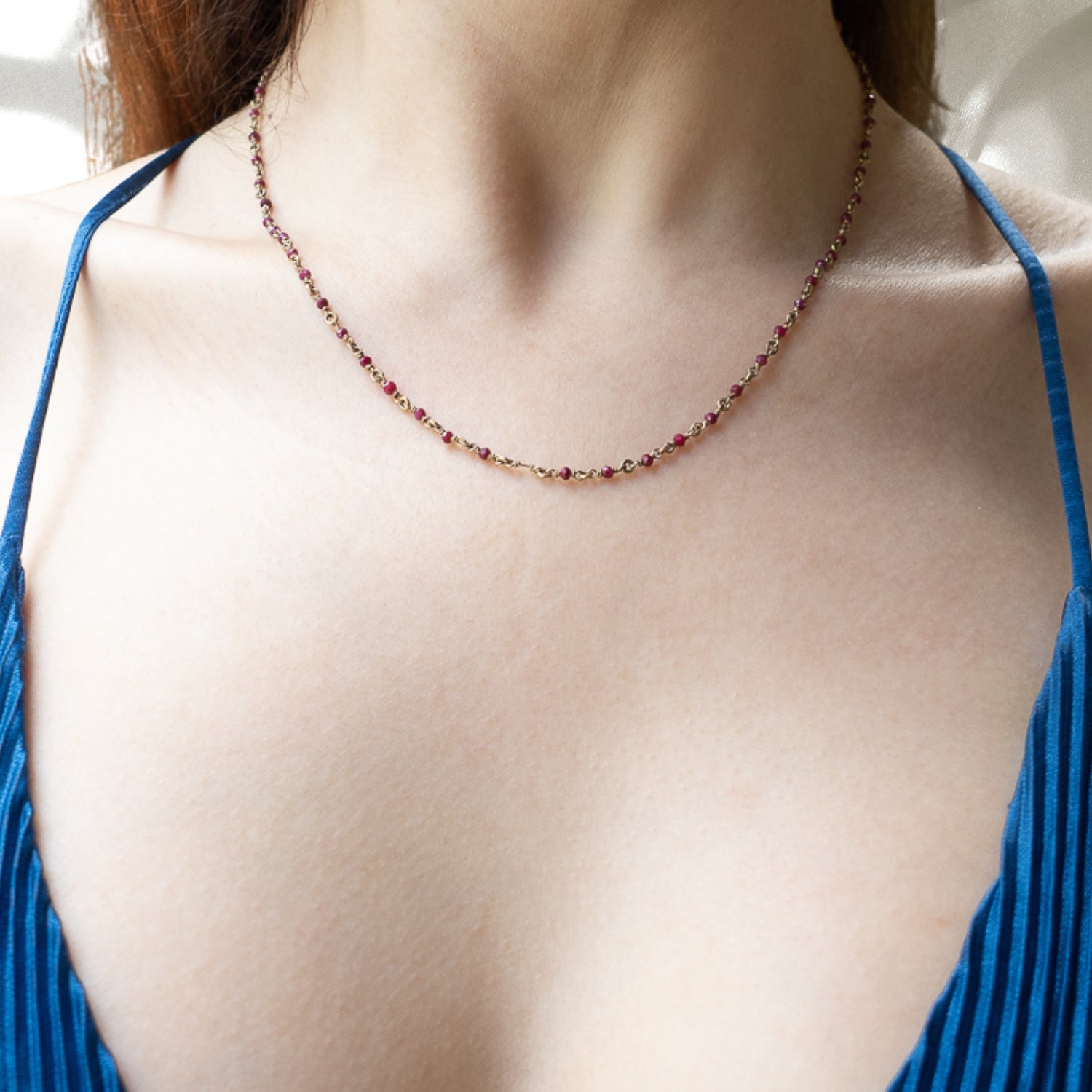 The Karya Ruby Gold Necklace beautifully adorns the neckline of the model, enhancing her natural beauty and adding a touch of luxury to her ensemble.