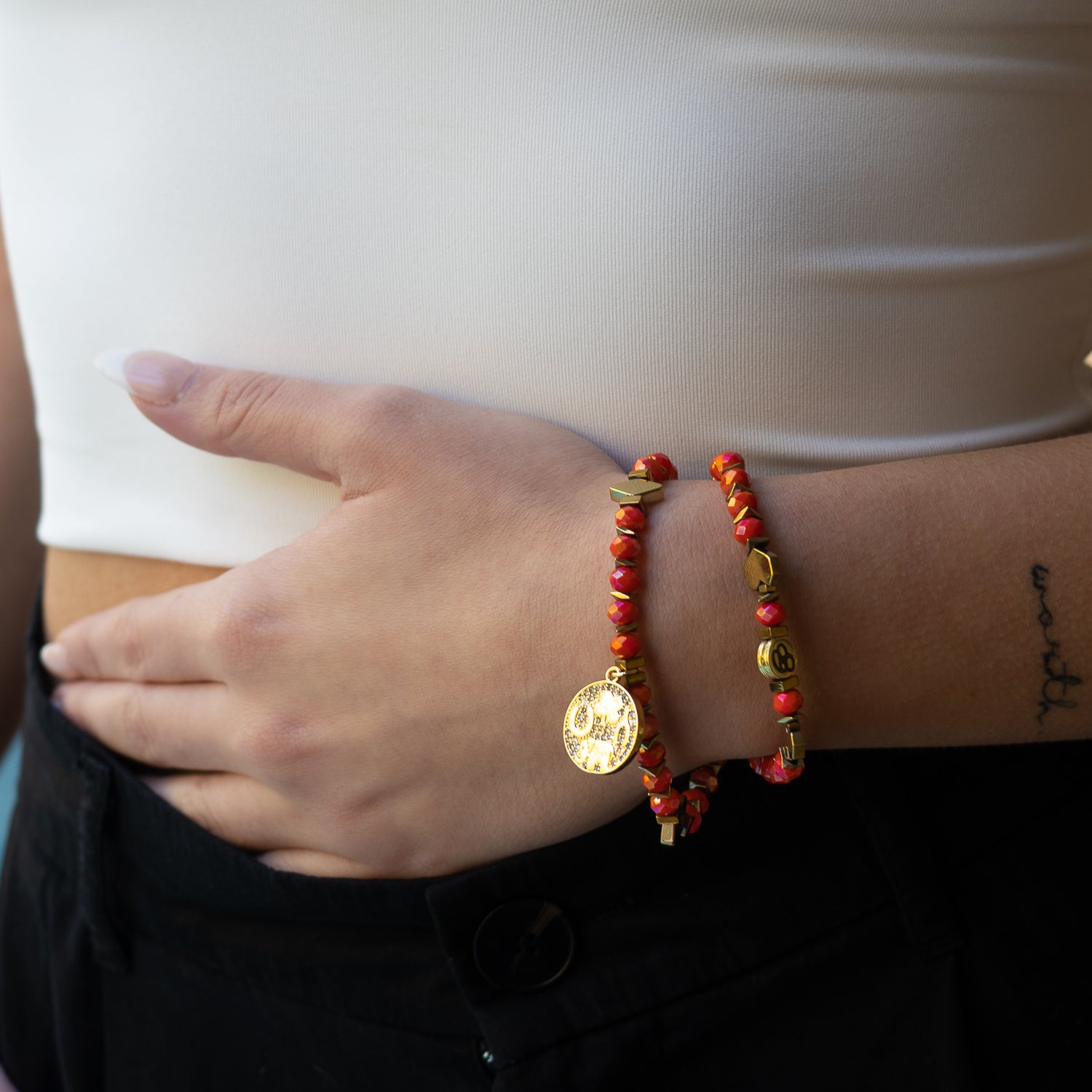 Model wearing: Embrace positivity with the Lucky Symbol Bracelet, a vibrant accessory featuring orange crystal beads and a gold symbol charm, perfect for any occasion.