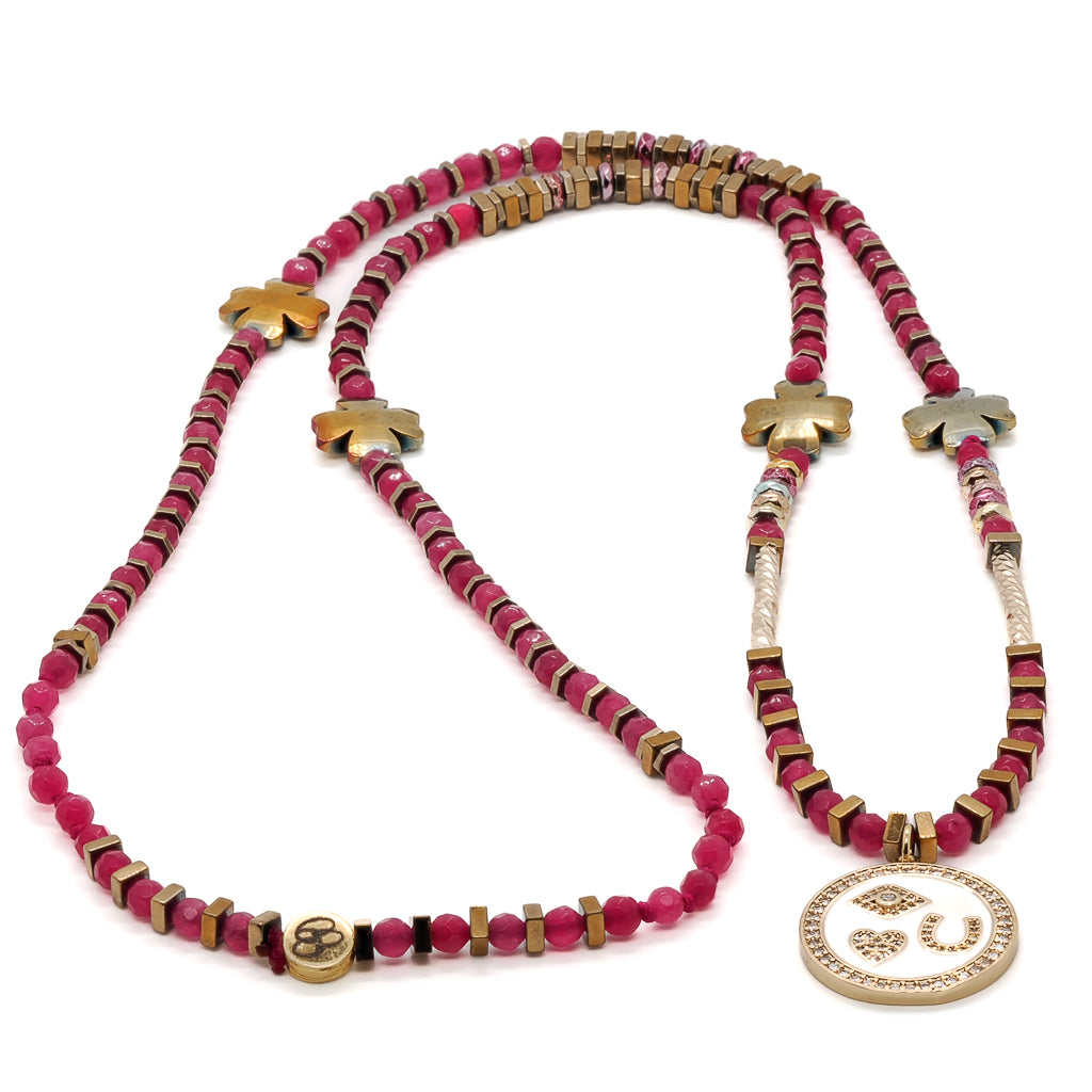 Adorn yourself with the Magic Blessings Pink Necklace, showcasing a collection of protective symbols including an evil eye, horseshoe, heart pendant, and lucky flowers, beautifully crafted with hot pink faceted jade stone beads and gold-colored hematite spacers.