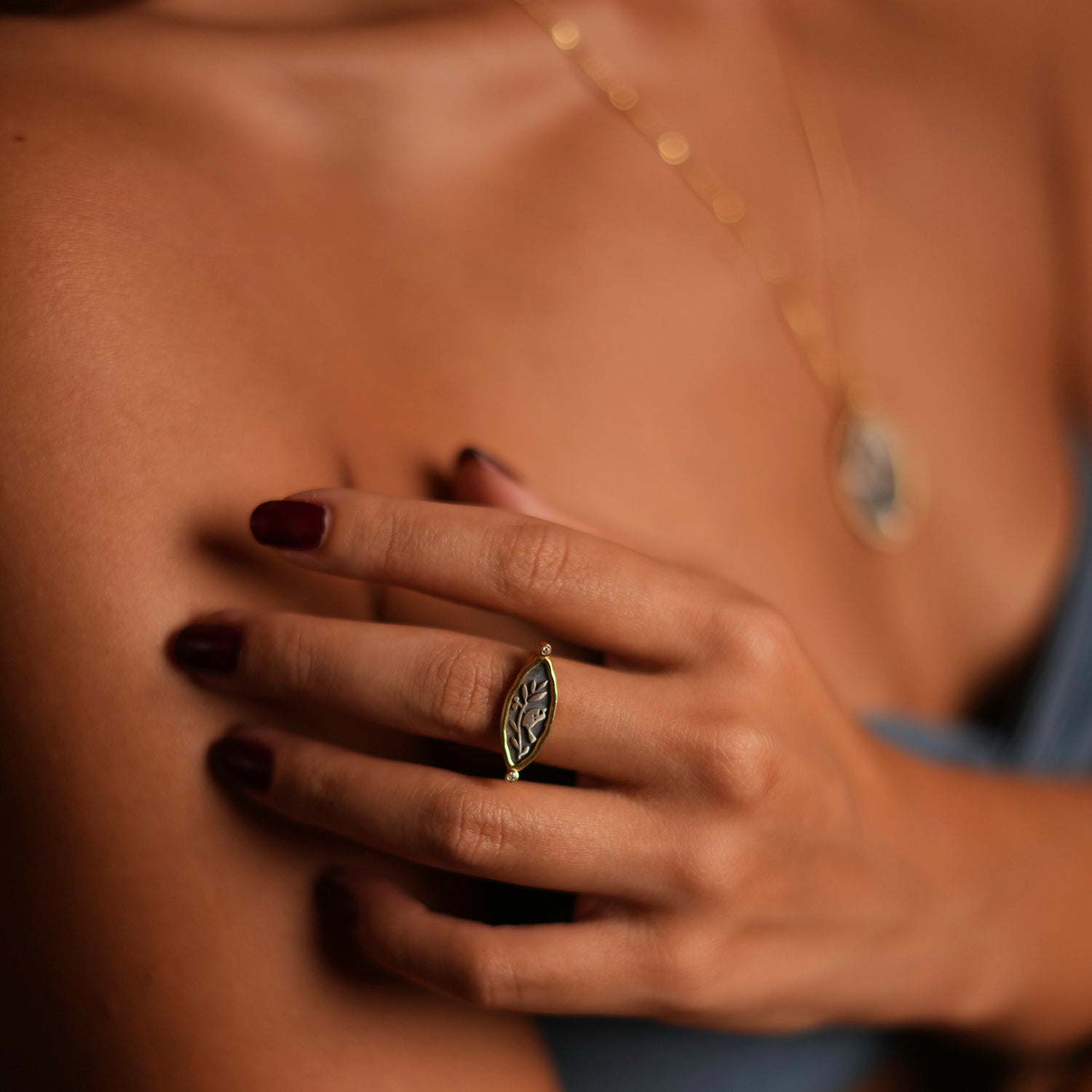 Elegant sterling silver signet ring featuring a detailed olive leaf and bird design, bordered with 18k gold plating