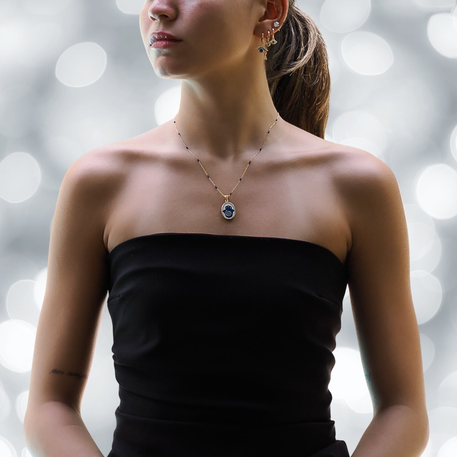 Stylish Model Sporting an Elegant Hamsa Hand Pendant Necklace with Blue Enamel.