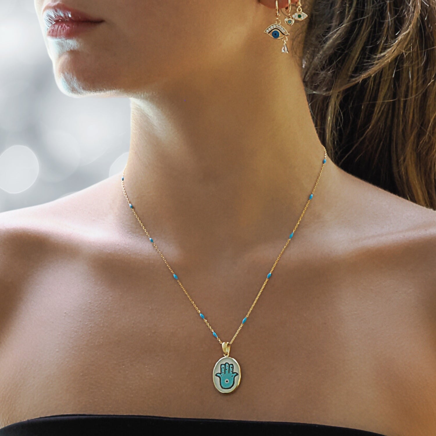 Stylish Model Sporting an Elegant Hamsa Hand Pendant Necklace with Turquoise Enamel.