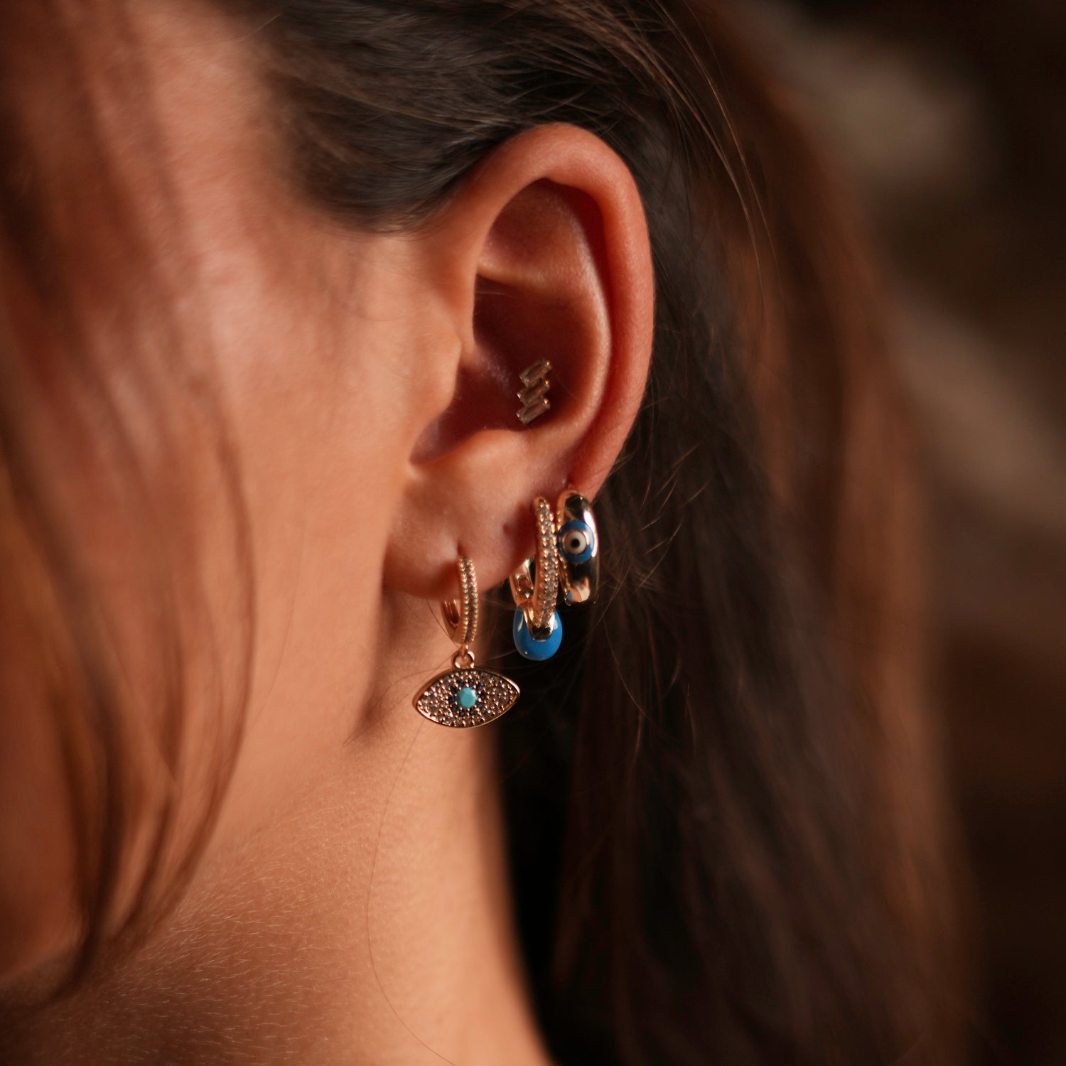 Blue Evil Eye gold hoop earrings set with diamonds, offering style and spiritual significance.