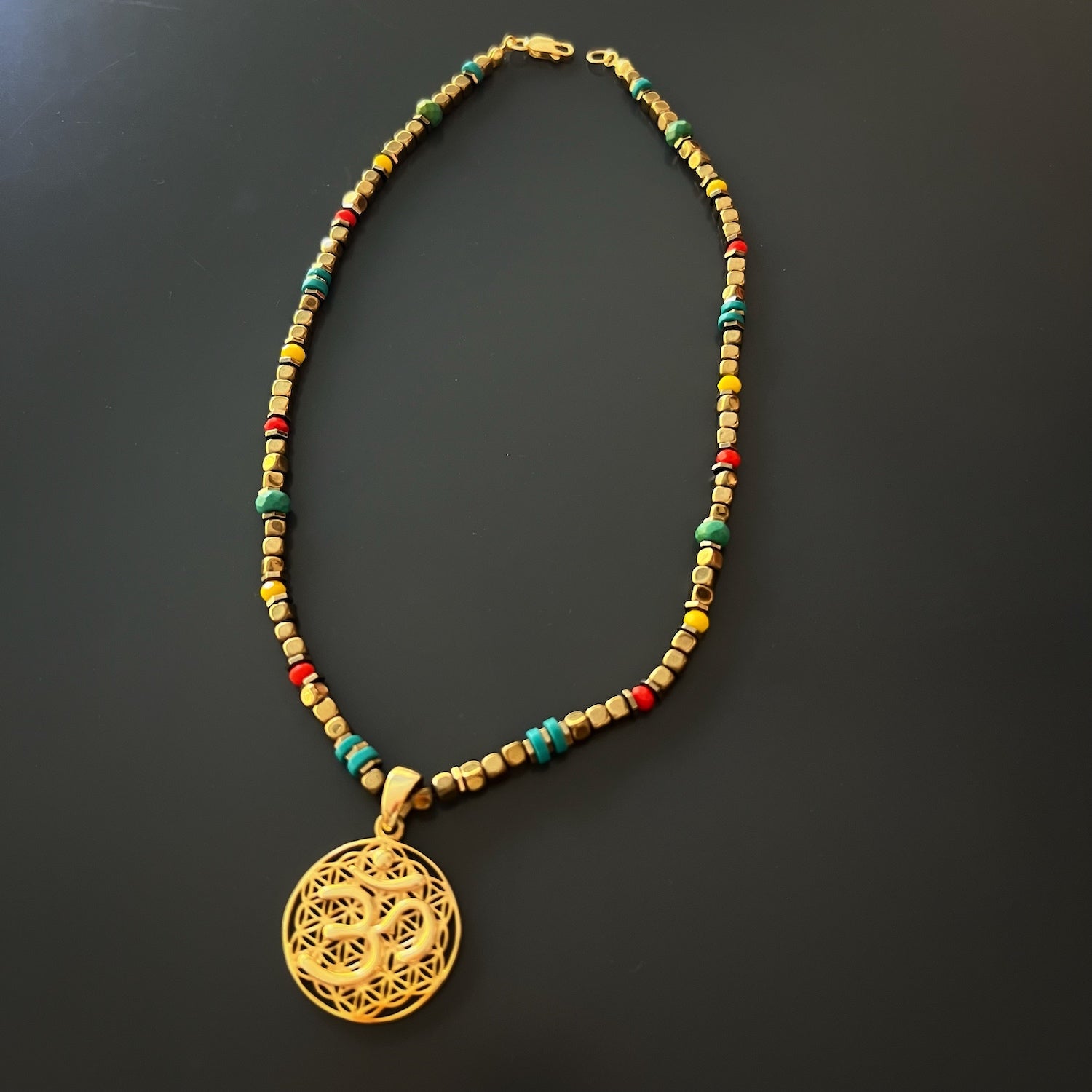 Turquoise stone beads, known for their calming properties, creating a visually appealing contrast with the gold elements in the Breathe Om Gold Necklace.