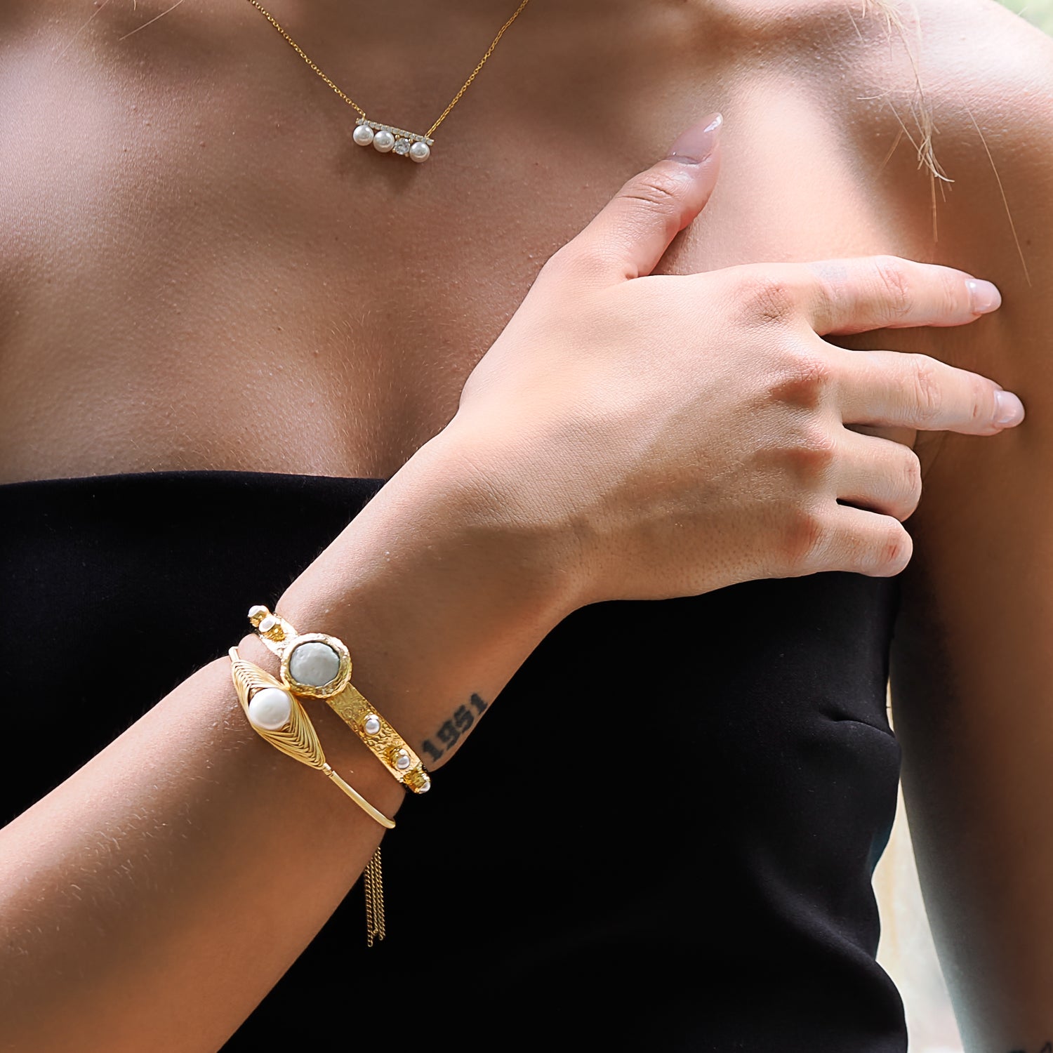 Model radiates elegance with the opulent Cleopatra Gold and Pearl Bangle Bracelet.