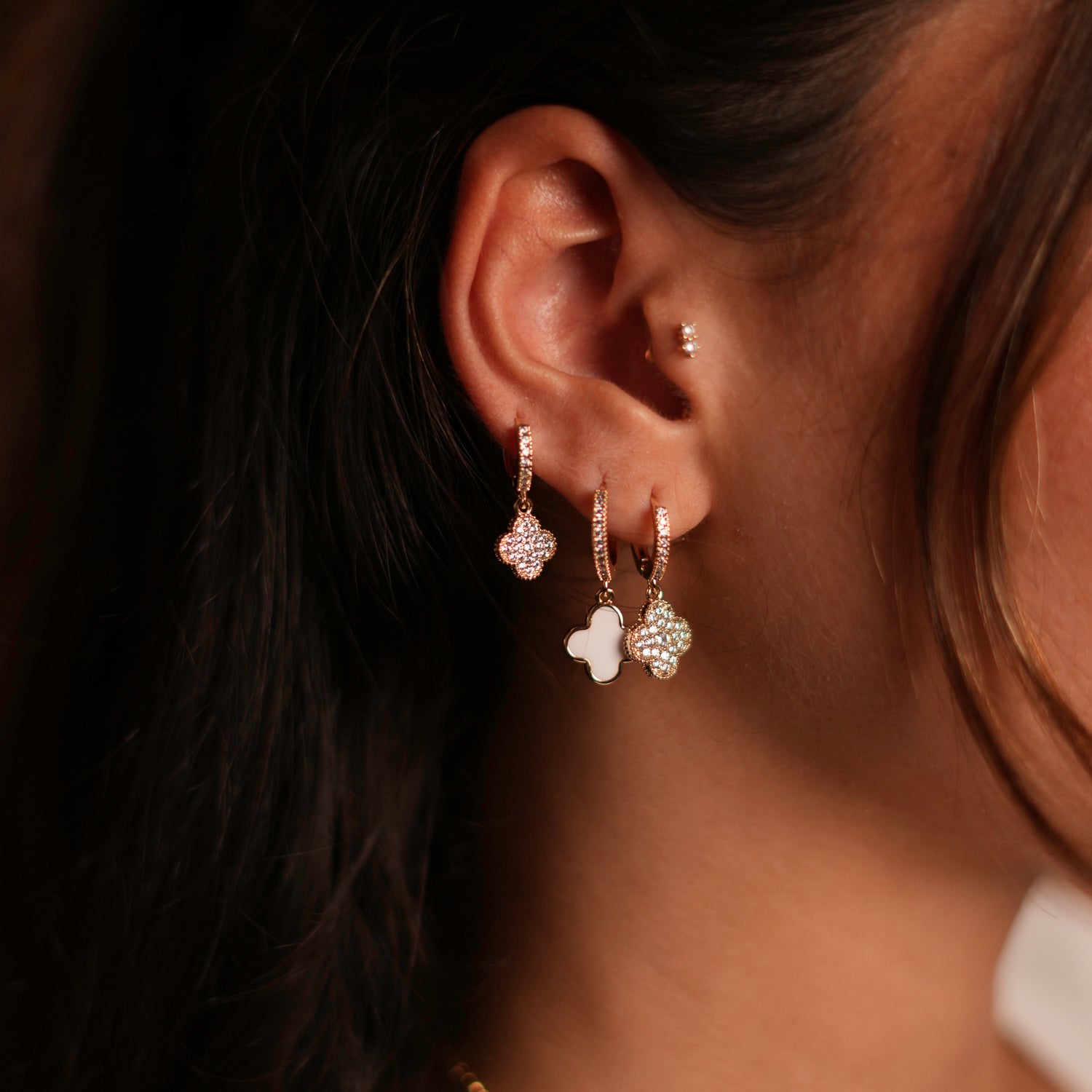 Elegant clover gold hoop earrings, set with CZ diamonds and white enamel, designed for a chic and lucky look.