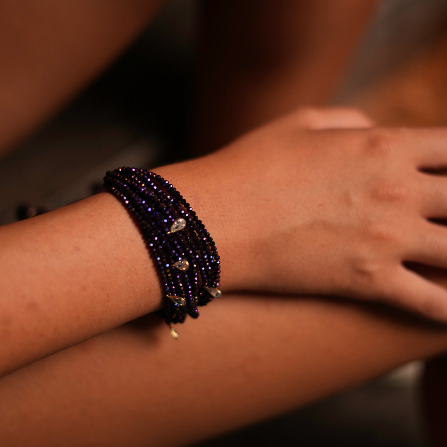 Handcrafted purple crystal bracelet with silver and Swarovski charms, featuring playful cotton tassels