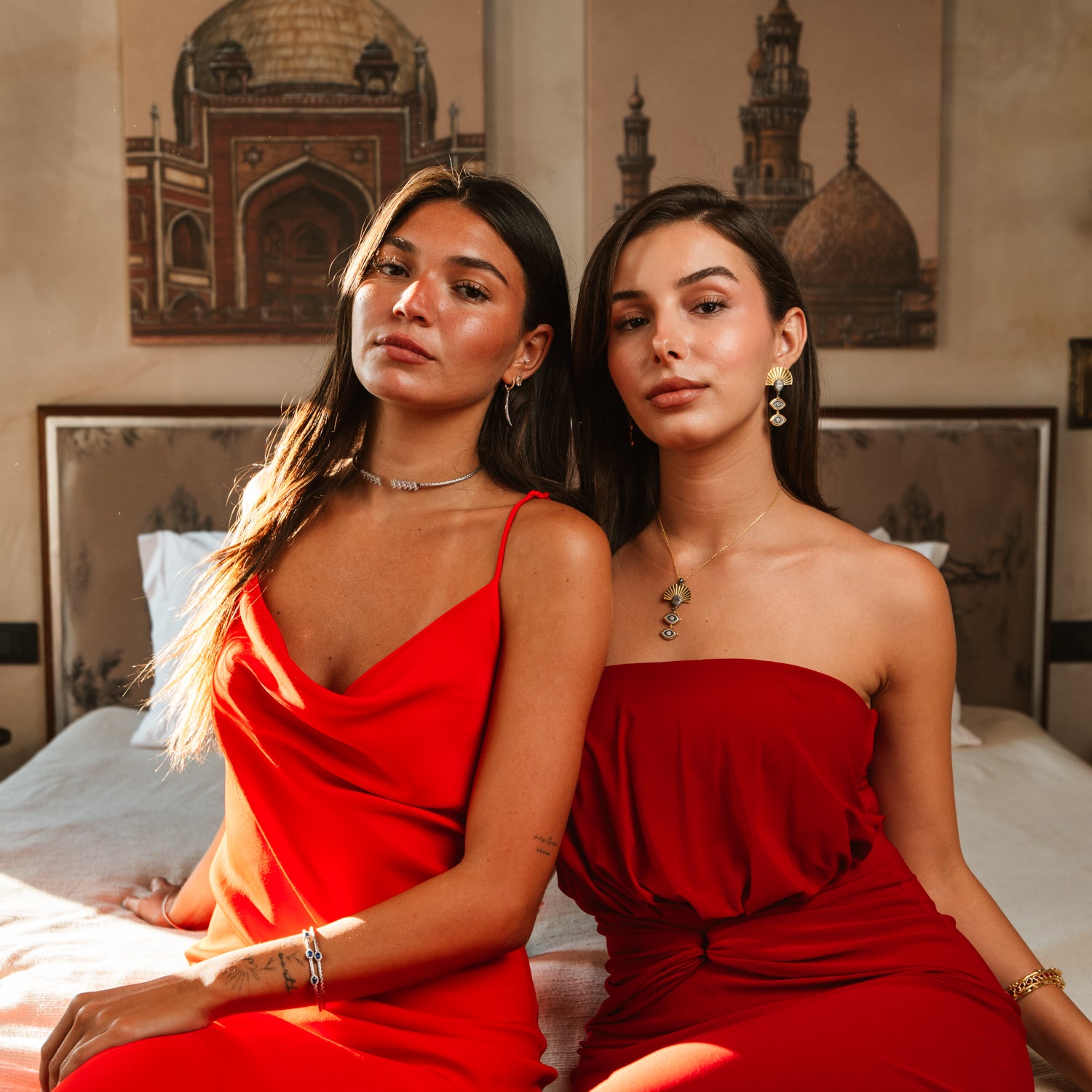 Two models wearing Ebru Jewelry pieces including the Sunray Ancient Eye Two-Tone Pendant Necklace, styled in red dresses