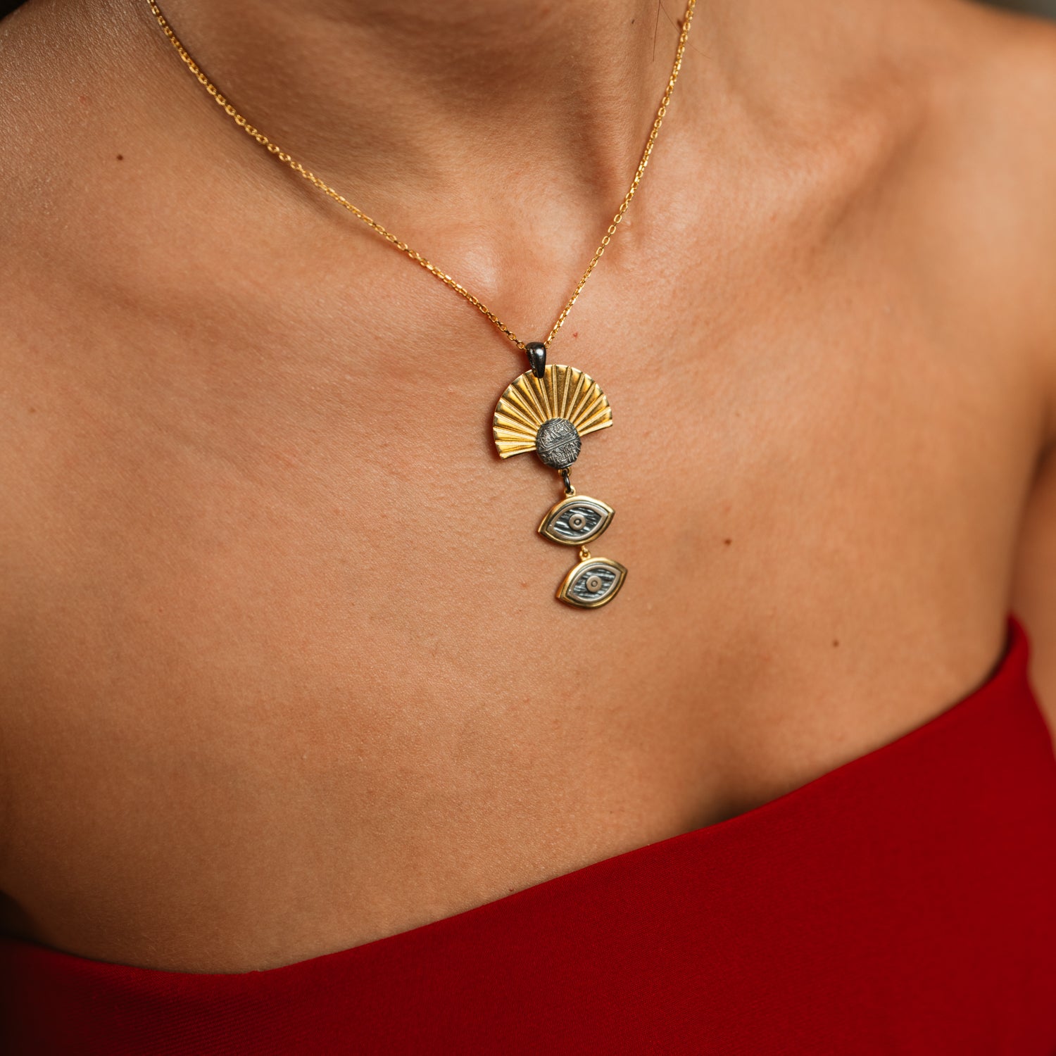 Macro close-up of the Sunray Ancient Eye Two-Tone Pendant Necklace on the collarbone, showing the gold sunray and oxidised silver coin detail