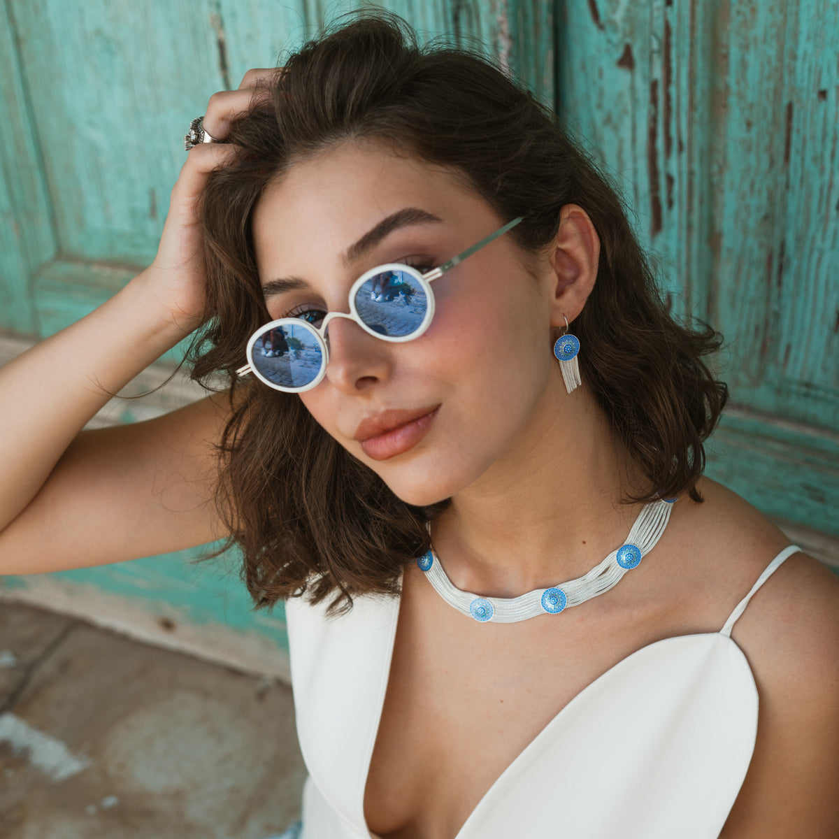 Model with hand in her hair wearing the Cobalt Bloom tassel earrings and enamel choker