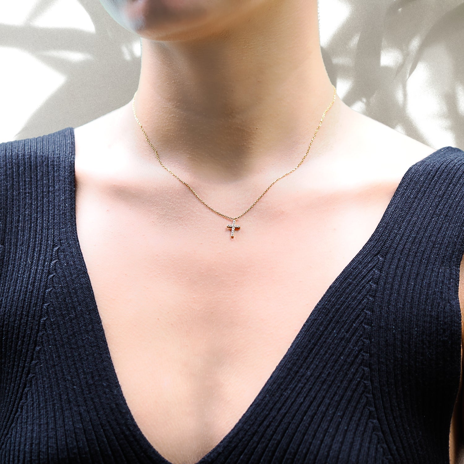 A model wearing the Dainty Diamond Cross Necklace. The necklace beautifully drapes around the neck, showcasing the delicate cross pendant with the shimmering CZ diamond.