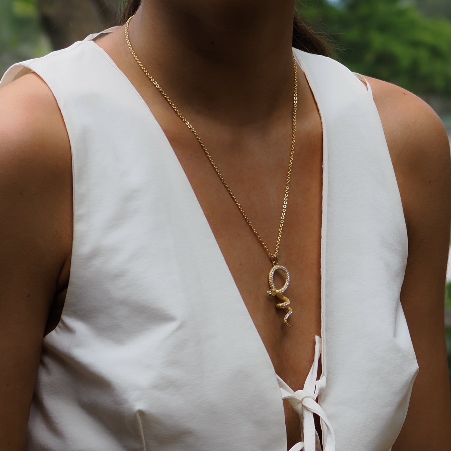 Elegant snake pendant necklace with sparkling CZ diamonds, emerald stones, and a thick gold vermeil chain.

