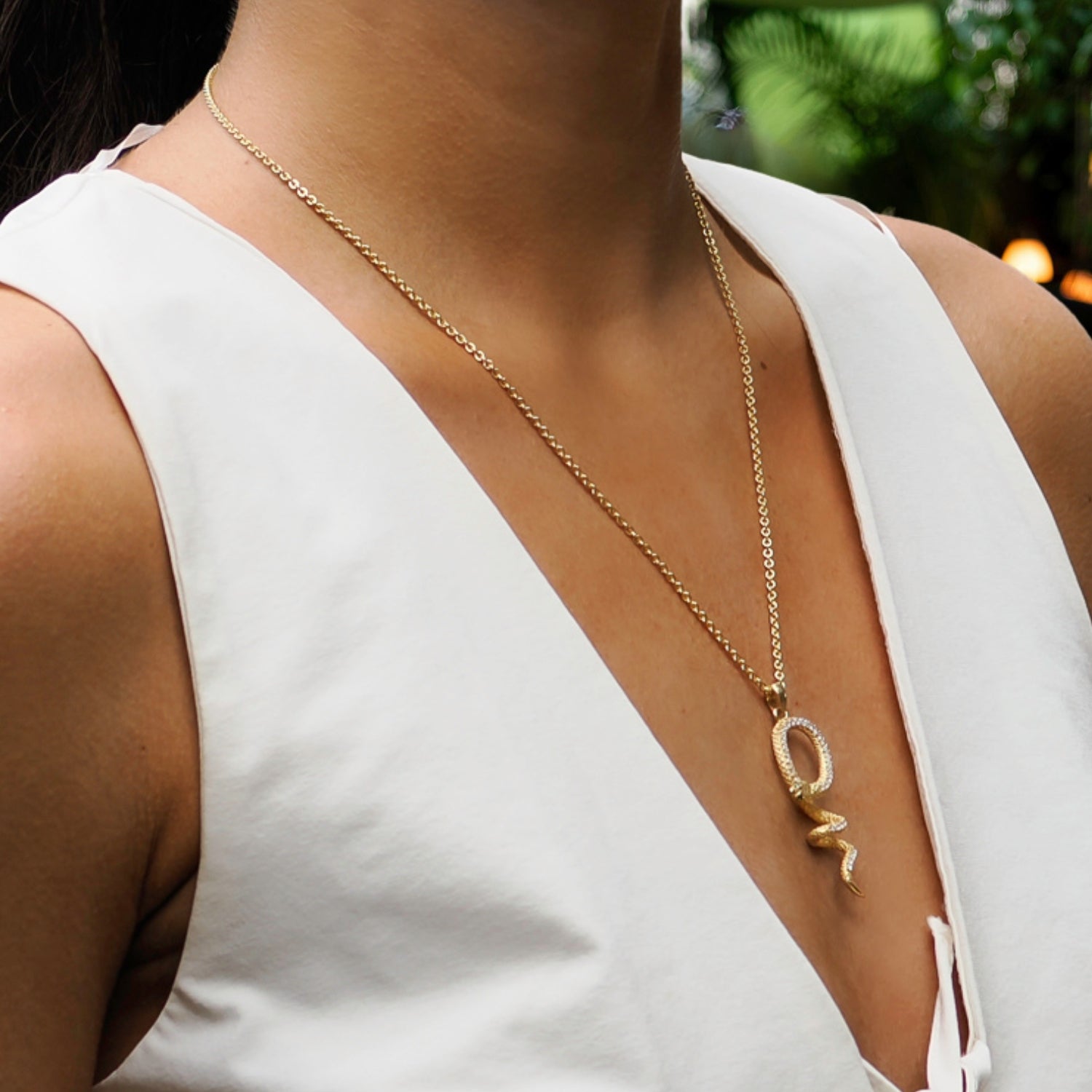 Gold vermeil snake necklace with a bold chain and pendant featuring diamond details and emerald accents.
