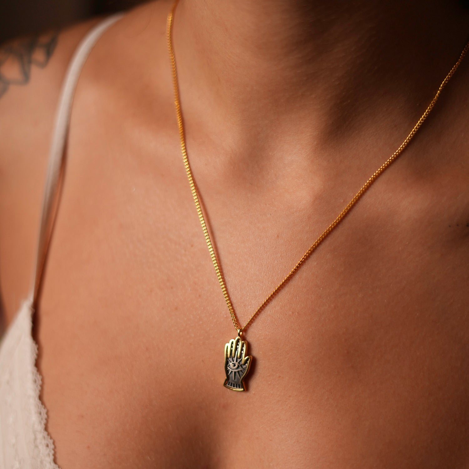 Stylish sterling silver necklace with a gold vermeil chain and a hand-shaped pendant featuring a protective evil eye, symbolizing watchful guardianship.