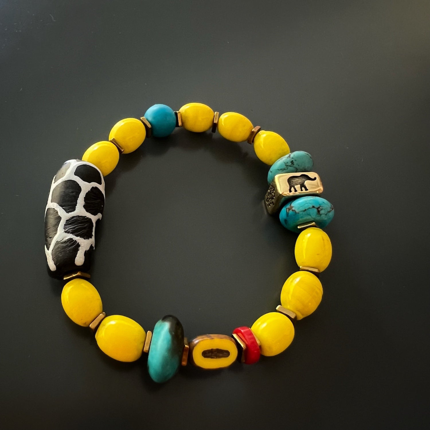 Top-down view of the Happiness Symbol Yellow Bracelet, displaying the beautiful arrangement of the yellow African color beads, the turquoise stone beads, and the unique ceramic beads, creating a joyful and eye-catching design.