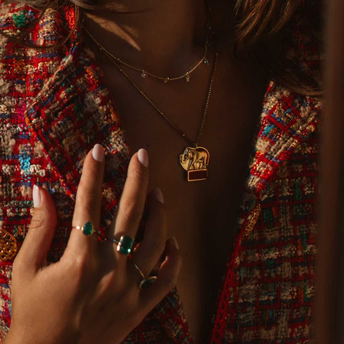 Close view of the Lucky Elephant Red Coral Gold Pendant Necklace resting on the chest, the coral bar catching the light