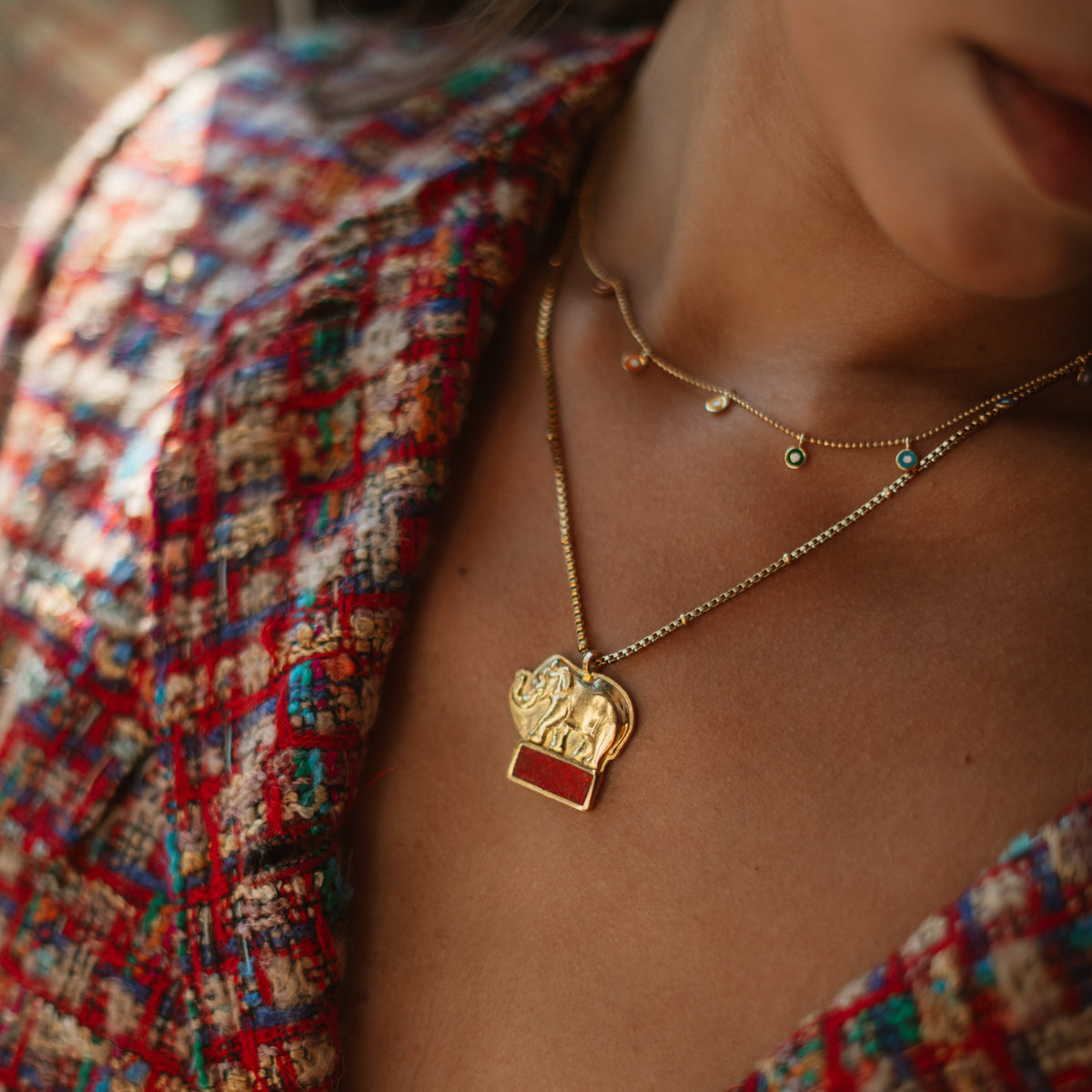 Lucky Elephant Red Coral Gold Pendant Necklace worn on the neck, layered with a fine gold chain