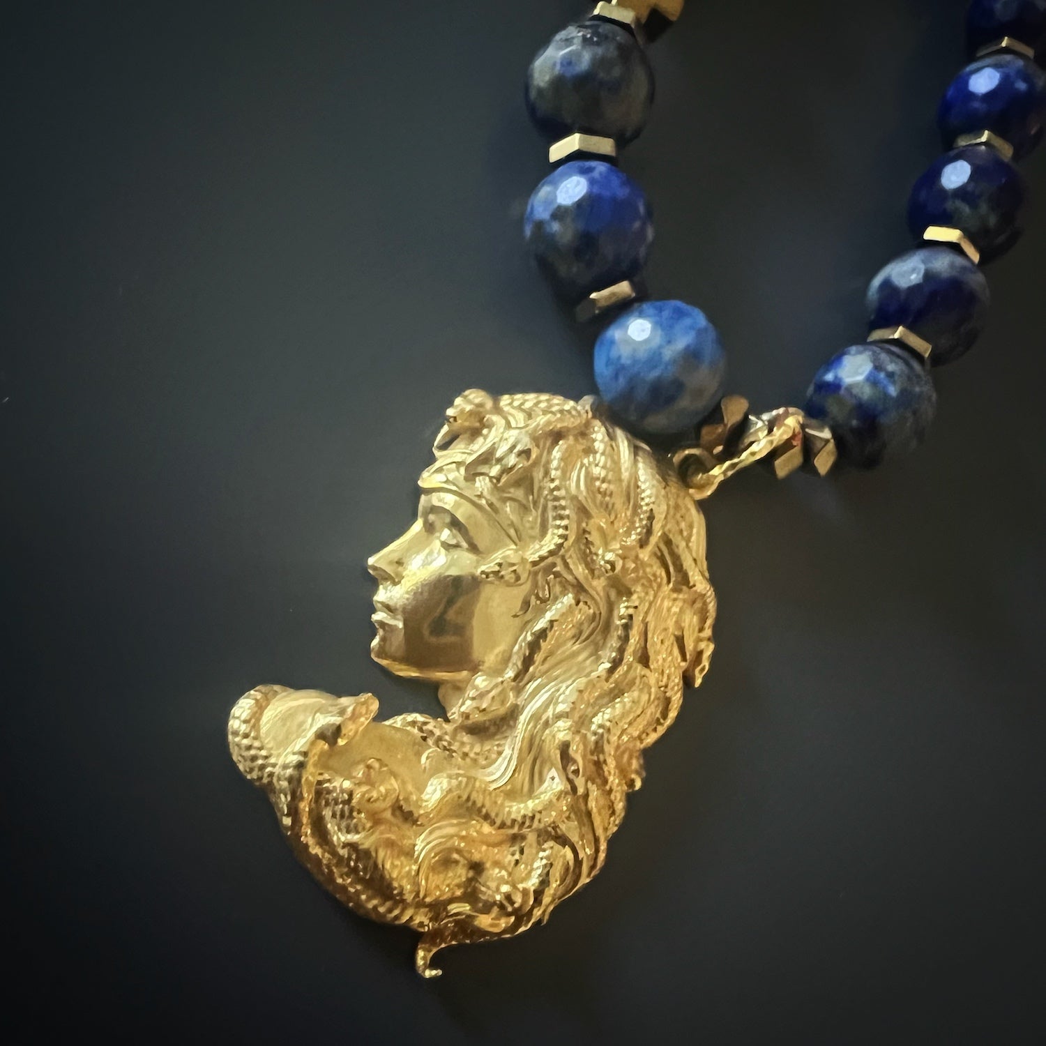 Embrace the enchanting allure of the Medusa Lapis Lazuli Necklace, featuring a sterling silver pendant and lapis lazuli stone beads.