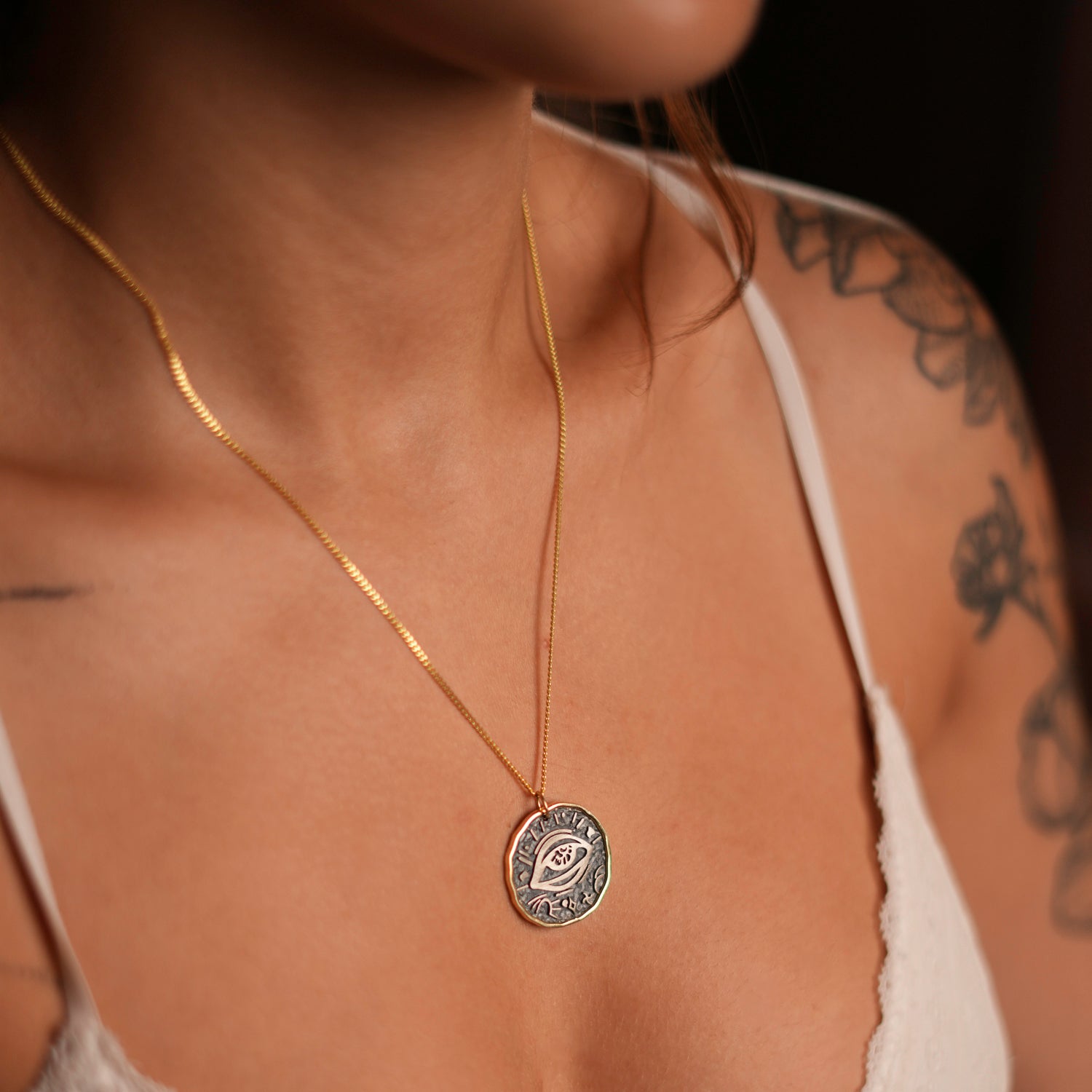 Sterling silver and gold necklace with a protective eye symbol, crafted to shield and empower the wearer.