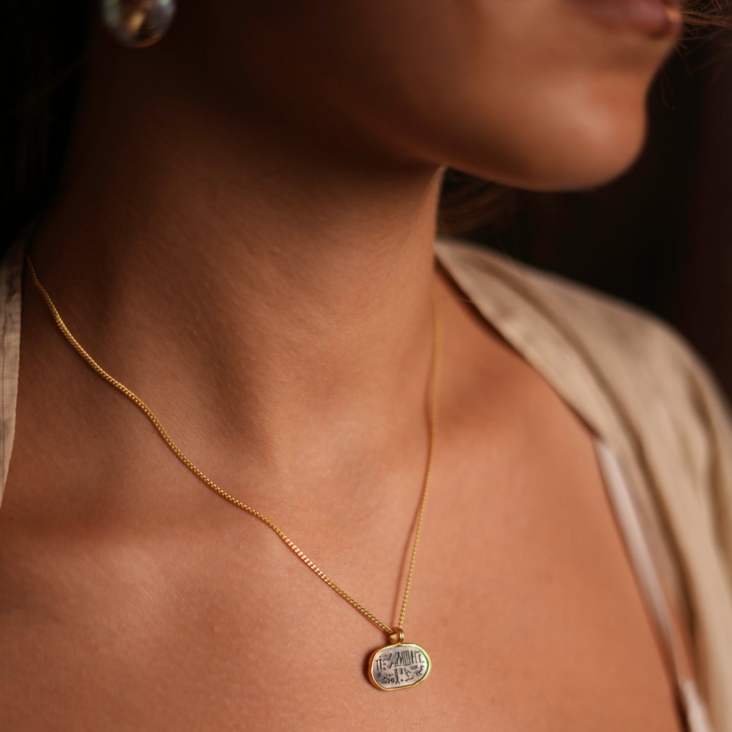 Oval-shaped pendant with Egyptian symbols on a gold-plated chain, designed for subtle spiritual strength.