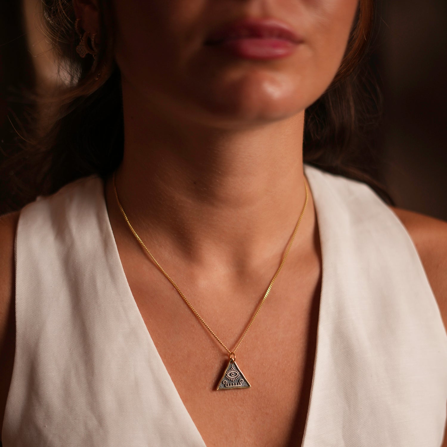 Minimalist sterling silver pendant with the Third Eye symbol, paired with an 18k gold-plated chain for a blend of sophistication and protection.