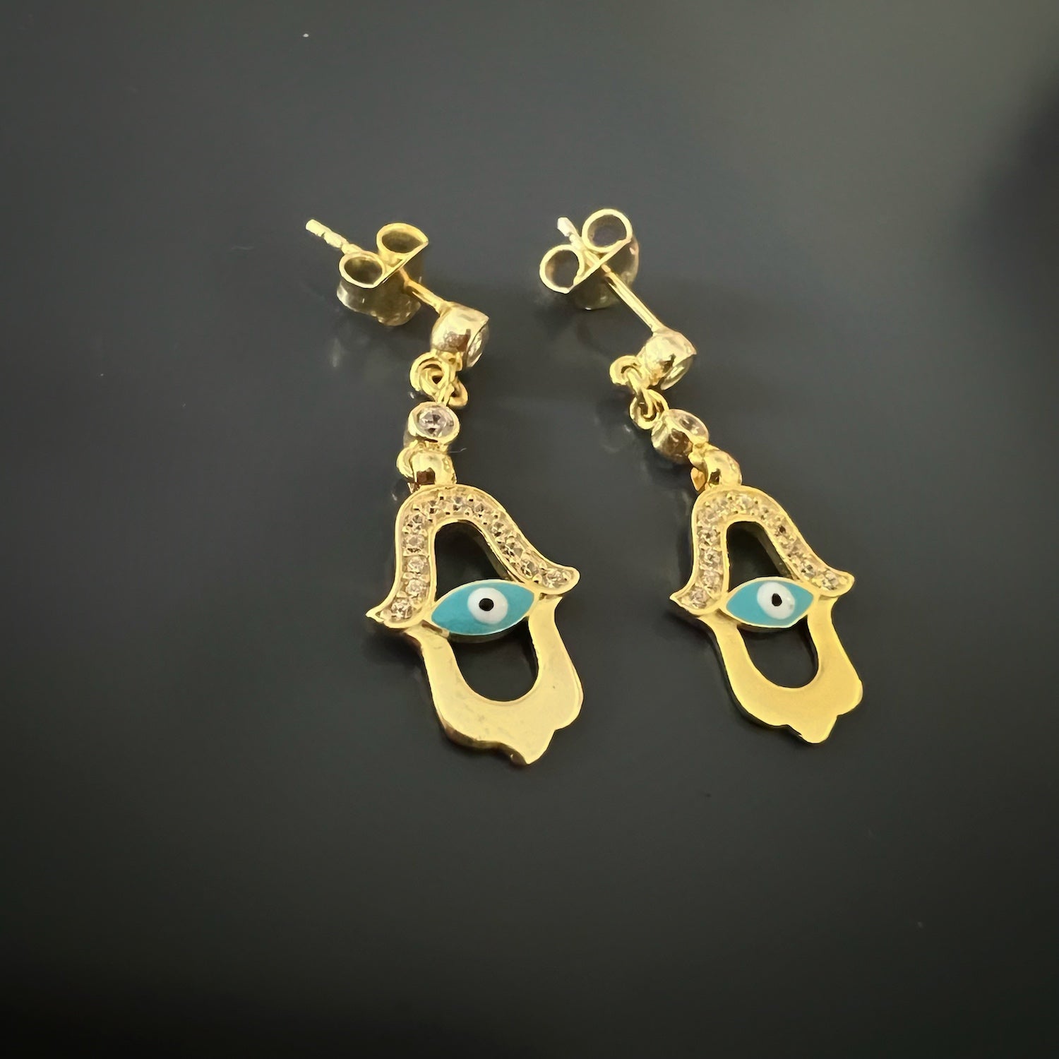 Luxurious sterling silver earrings plated in 18K gold, showcasing the vibrant turquoise enamel Evil Eye and Hamsa symbols
