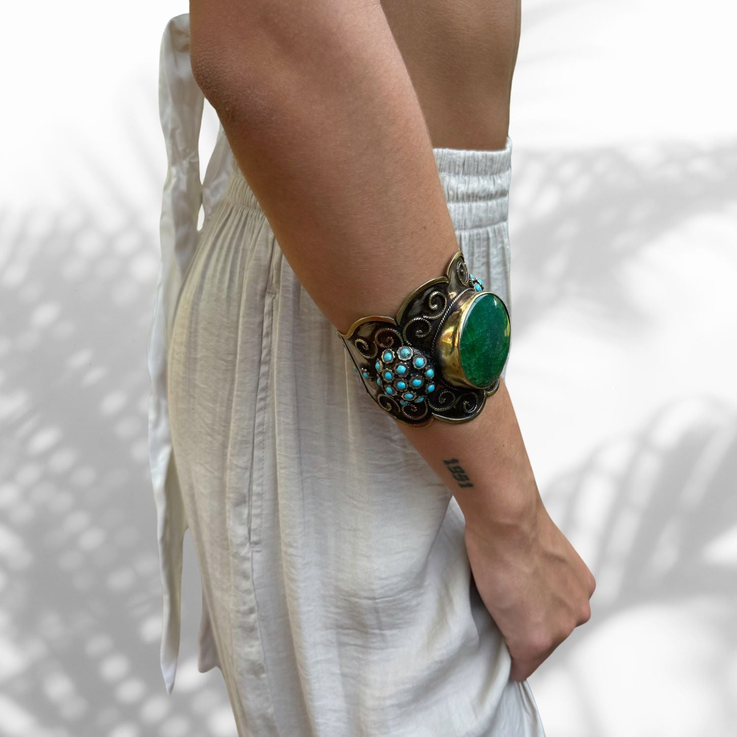 Model Wearing turquoise and jade gemstone bracelet with gold-plated designs
