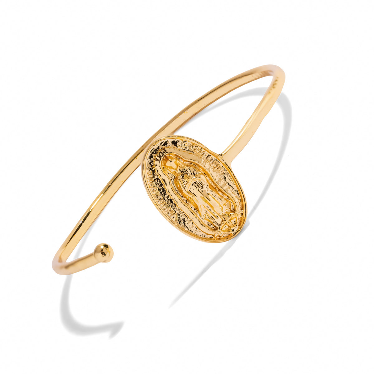 Virgin Mary medallion gold cuff bracelet laid diagonally on white