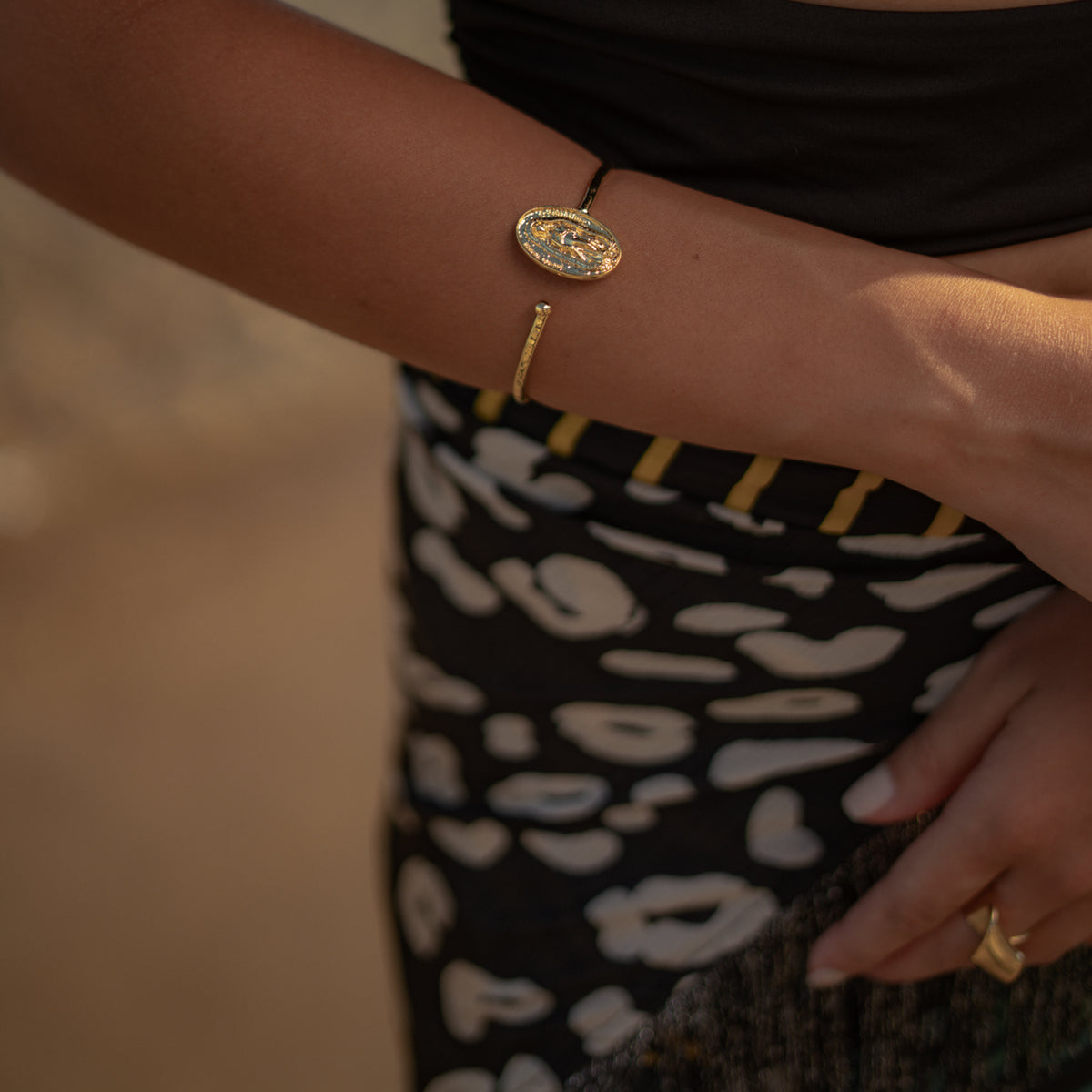 Model with a hand on her hip wearing the Virgin Mary Medallion Gold Bangle Bracelet