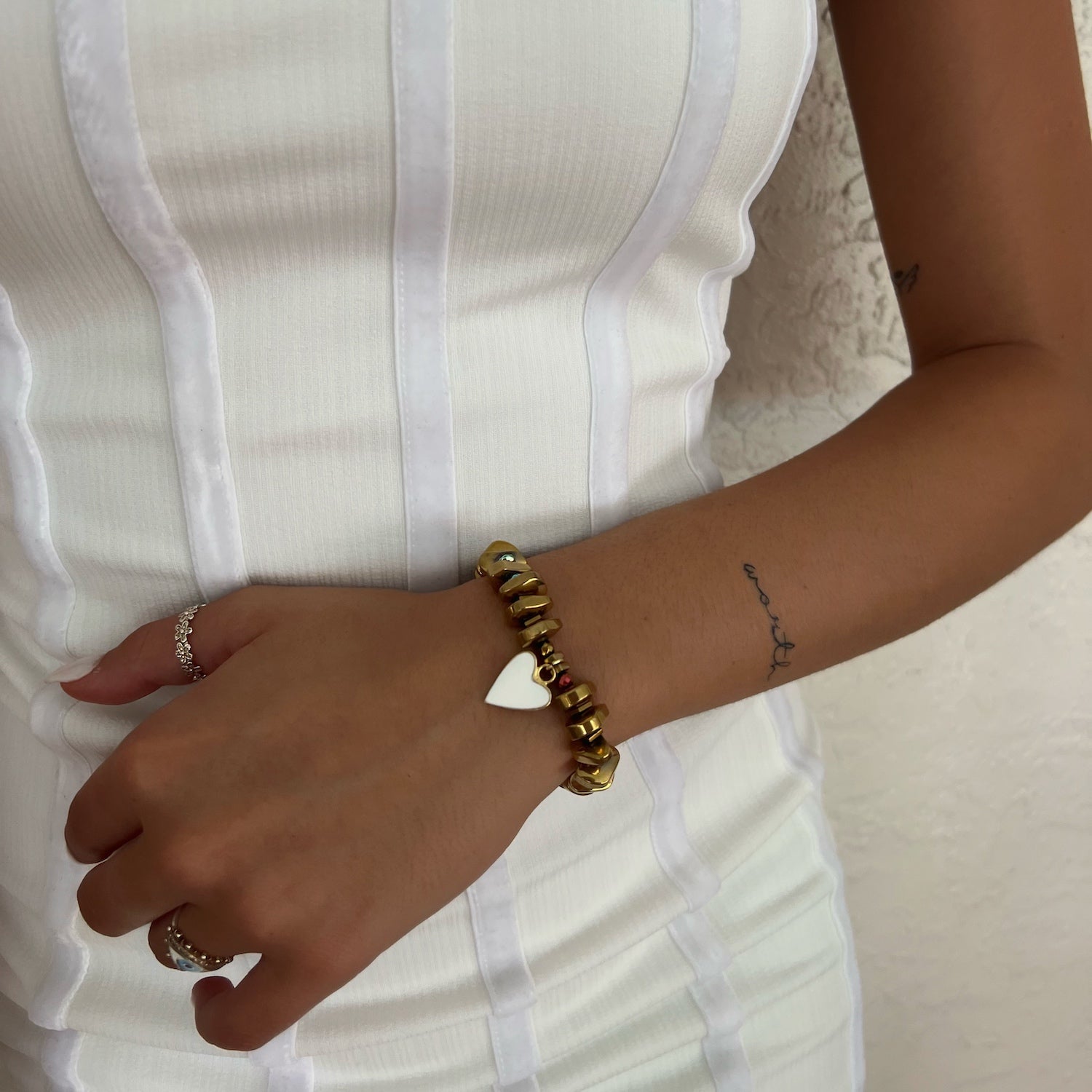 With the White Corazon Bracelet, the hand model exudes a sense of style and warmth, showcasing the charm&#39;s white enamel heart design.