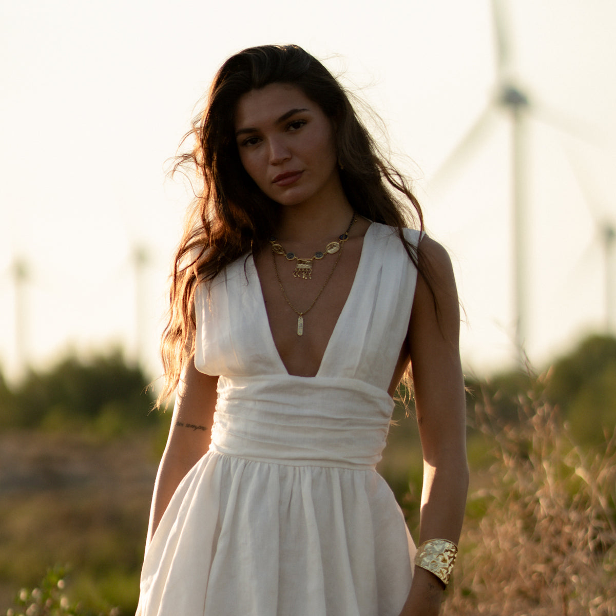 Model in a white dress at golden hour wearing the Amulet Gathering Evil Eye & Ruby Fringe Two Tone Necklace