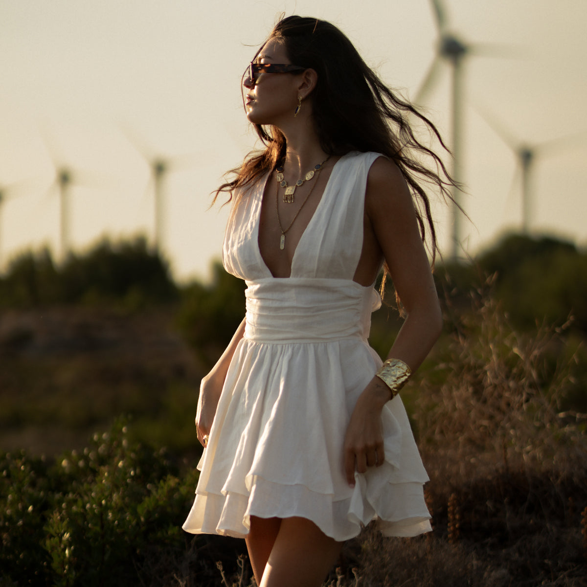 Woman in sunglasses and a white dress wearing the Amulet Gathering Evil Eye &amp; Ruby Fringe Two Tone Necklace outdoors