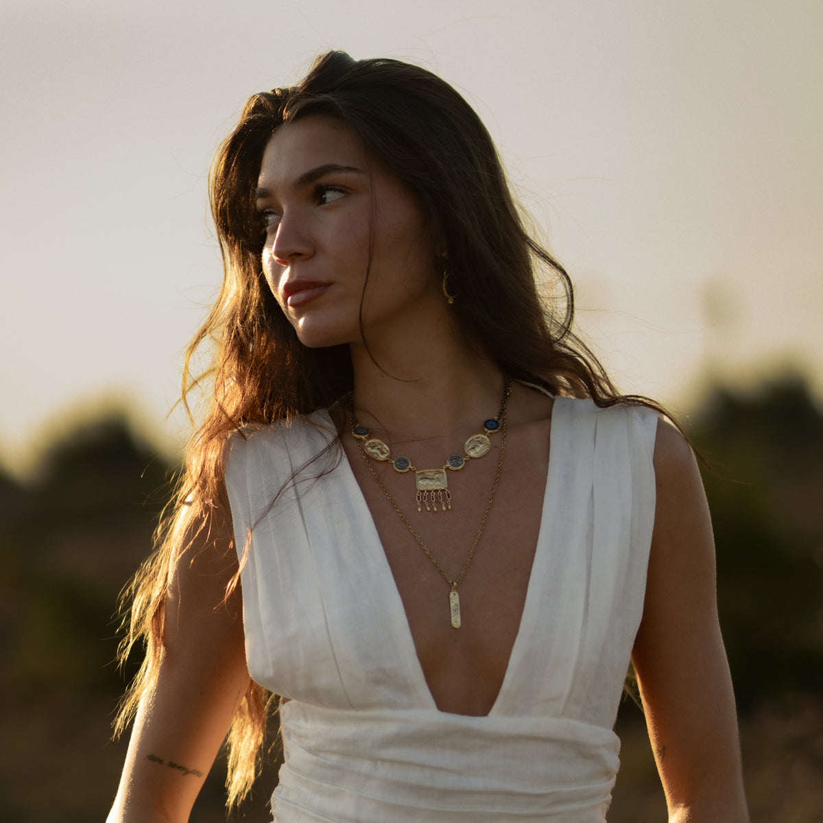 Model wearing the Amulet Gathering Evil Eye &amp; Ruby Fringe Two Tone Necklace layered over a longer gold tablet pendant