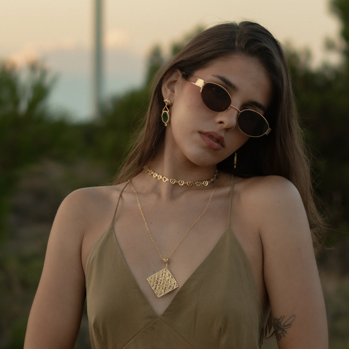 Model in an olive slip dress wearing the Ancient Rhythm Spiral Gold Link Chain Necklace layered with a long gold pendant