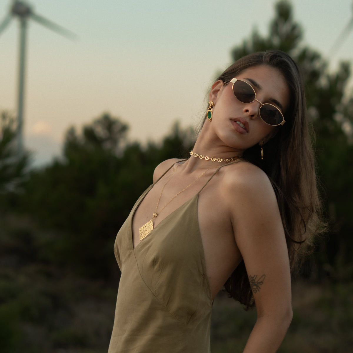 Model at sunset wearing the Ancient Rhythm Spiral Gold Link Chain Necklace with a long gold pendant and green jade earrings
