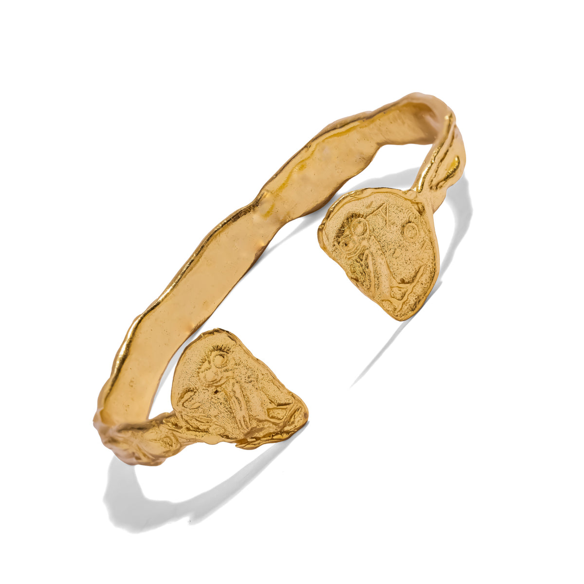 Side view of the open hammered gold cuff with two ancient style owl coins on a white background
