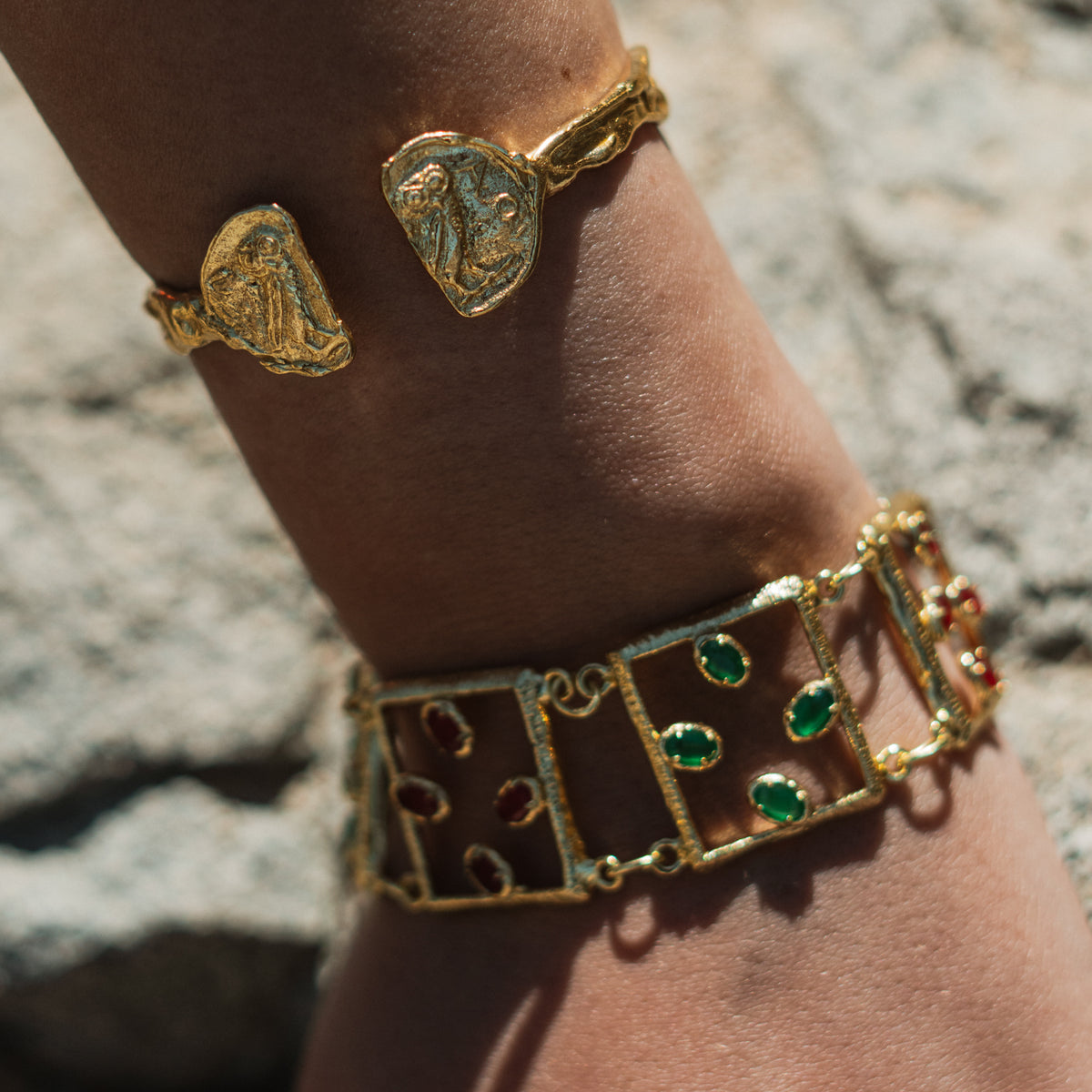 Close view of the Athena owl coin medallions on a sunlit forearm, stacked with a jeweled gold link bracelet