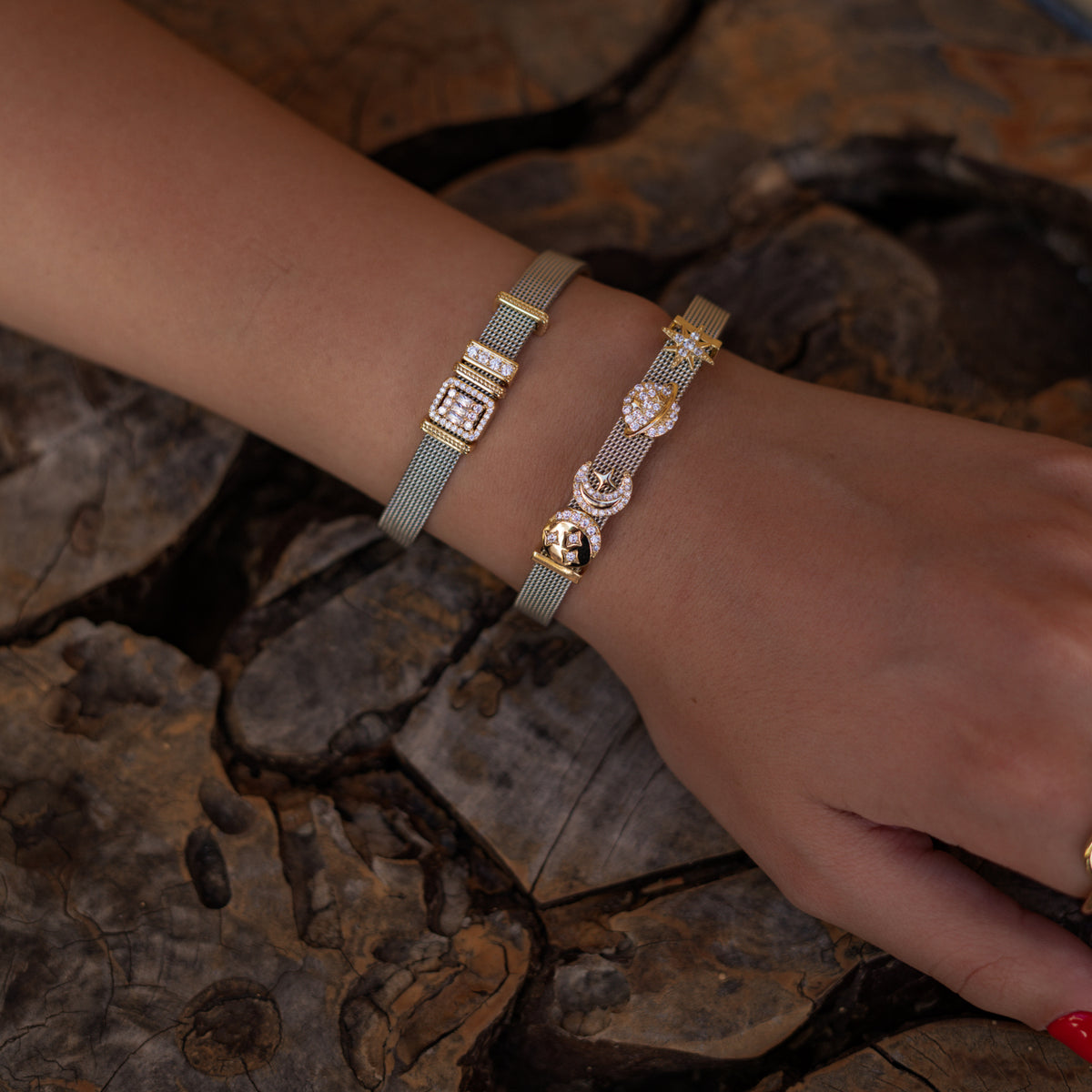 Baguette halo charm bracelet worn beside a celestial charm bracelet against weathered wood