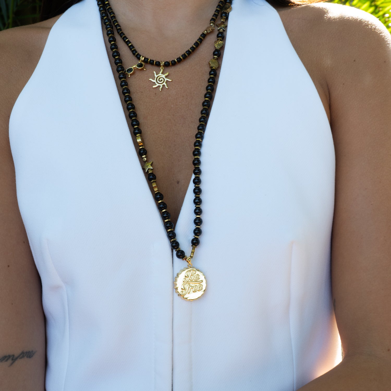Close-up of Be Free Onyx beaded long necklace styled with white halter and layered chokers